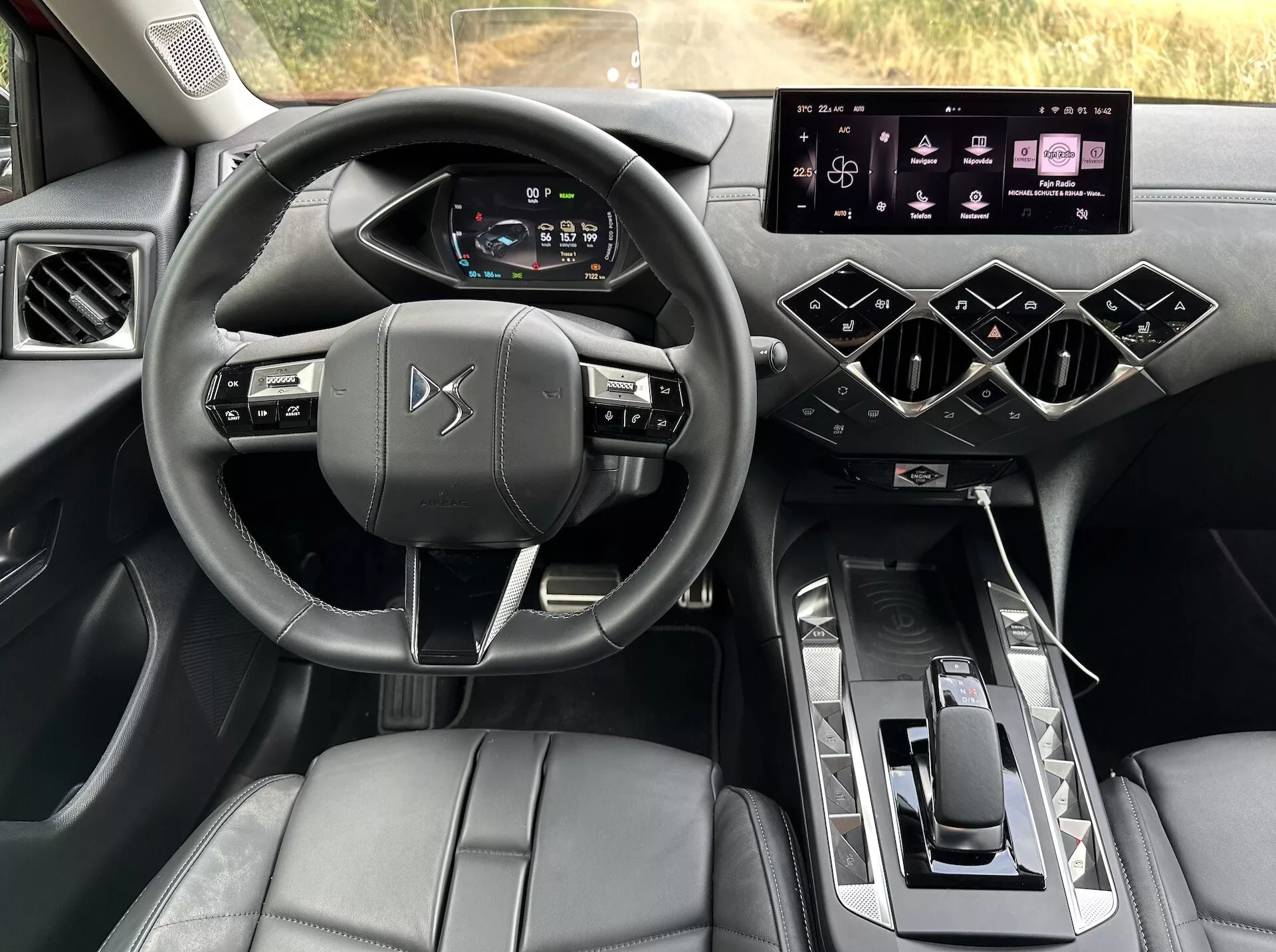 Notranji pogled na DS Automobiles DS-3 E-TENSE 2023, ki poudarja perspektivo voznika na volanu, digitalni armaturni plošči, infotainment sistemu in sredinski konzoli z luksuznimi zaključki in naprednimi tehnološkimi funkcijami