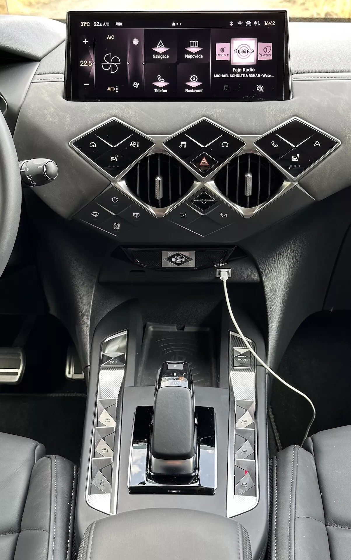 Pogled na notranjost DS Automobiles DS-3 E-TENSE 2023, ki poudarja sredinsko konzolo z zaslonom na dotik za infotainment, stilskimi zračniki, moderno prestavno ročico in sedeže iz premium usnja.