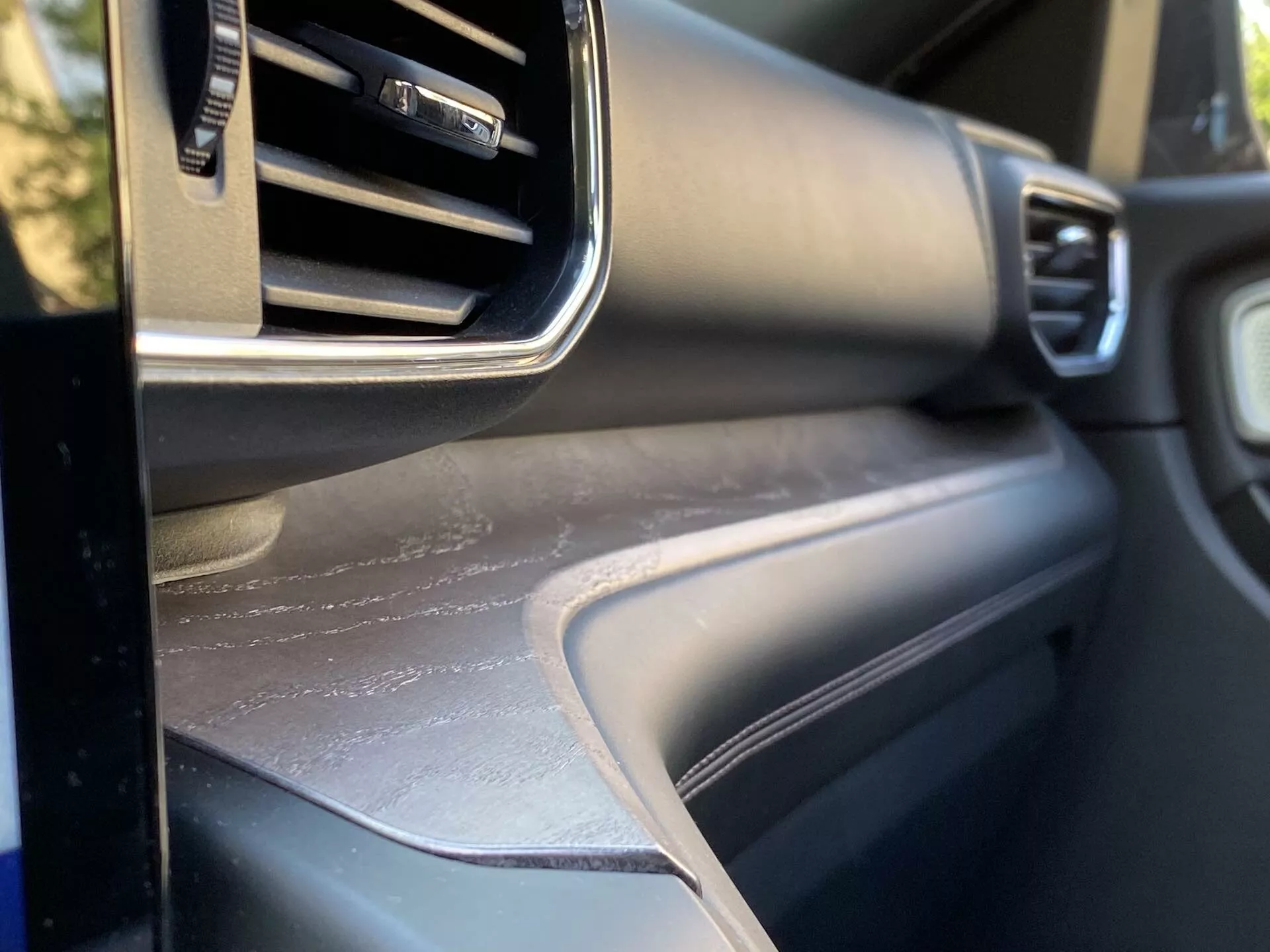 Pogled od blizu notranjosti vozila Ford Explorer 2019, osredotočen na področje armaturne plošče na sovoznikovi strani z nastavljivo odprtino za prezračevanje, kovinsko obrobo, teksturirano površino armaturne plošče in ujemajočo se ploščo vrat, ki prikazuje oblikovanje notranjosti in kakovost materialov vozila.