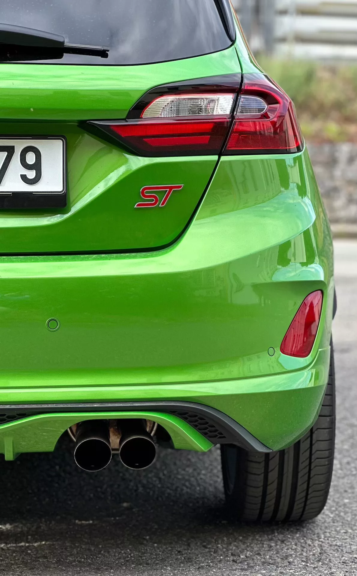 Podroben pogled na zadnji del Ford Fieste ST 2022 v svetle zeleni metalik barvi, ki prikazuje LED zadnje luči, dvojni krom izpuh in aerodinamični zadnji difuzor
