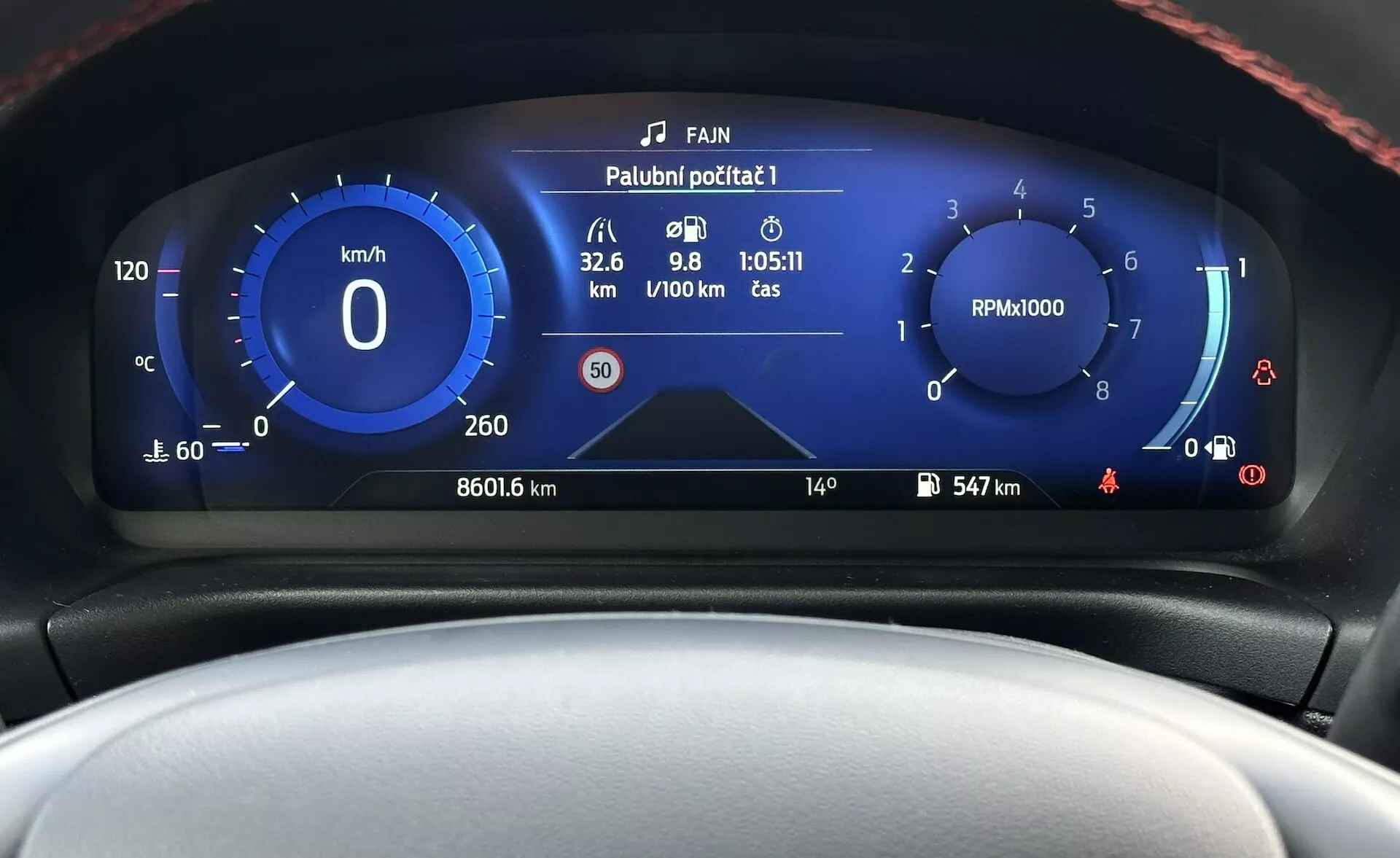 Digitalni instrumentni panel Ford Fieste 2022, ki prikazuje podroben sprednji pogled s hitrostomerom, tahometrom, merilcem učinkovitosti goriva in različnimi kazalniki stanja vozila v modernem dizajnu z modro-belo barvno shemo.