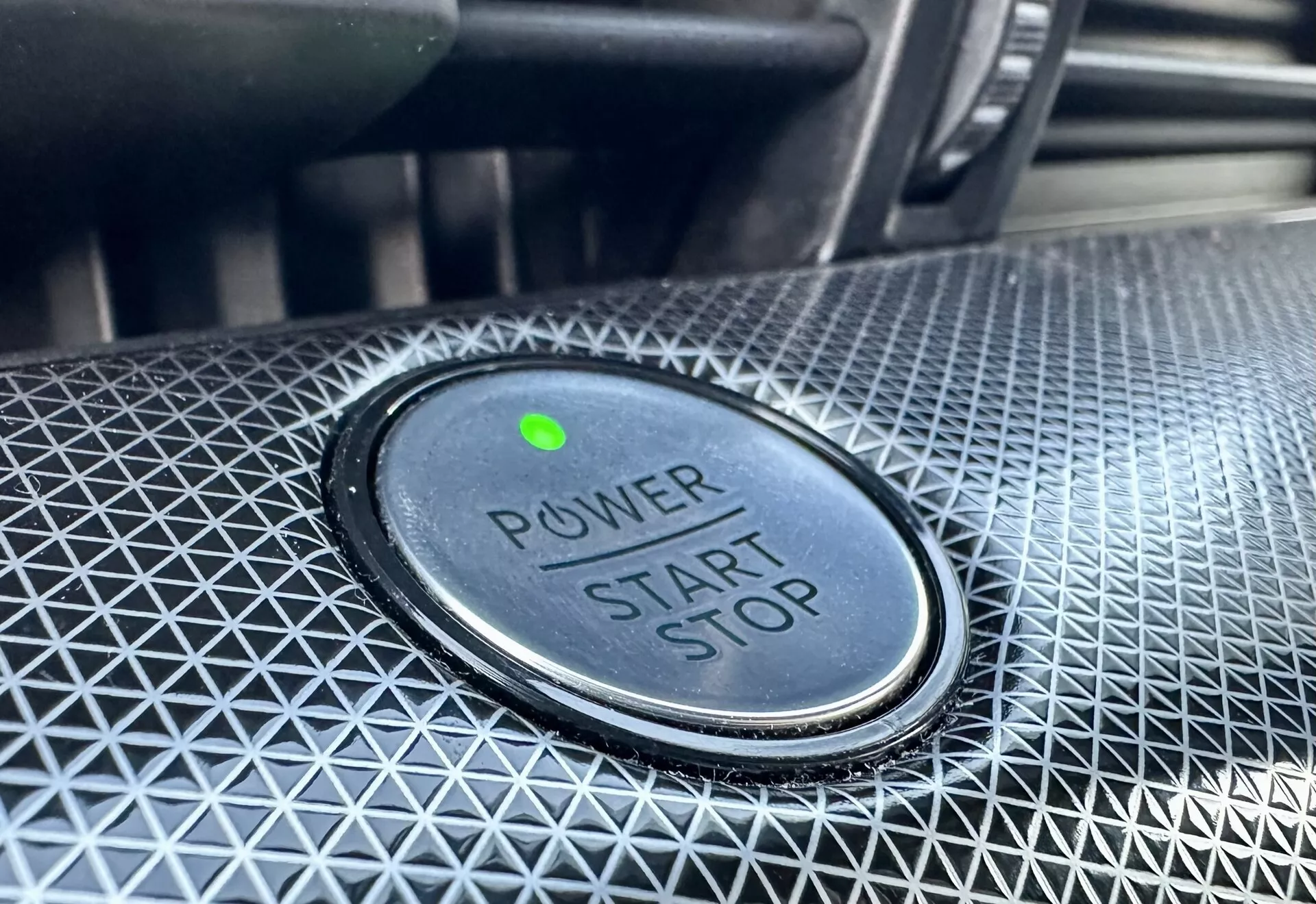 Pogled od blizu na gumb za zagon/ustavitev moči v Ford Mustang-Mach-E 2020, z napisom 'POWER START STOP', zeleno indikatorsko lučjo in teksturiranim oblikovanjem okolice