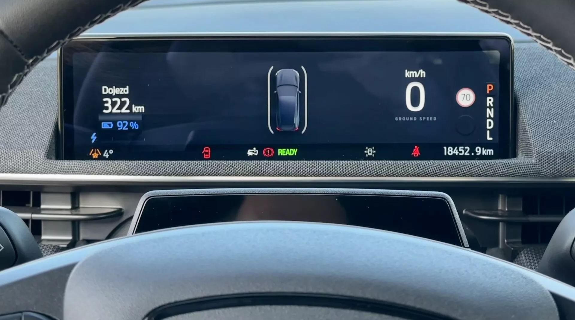 Digitalni prikazovalnik vozila Ford Mustang Mach-E 2020 iz perspektive voznika, ki prikazuje hitrost vozila 0 km/h, preostalo kapaciteto baterije 92%, skupno prepotovano razdaljo 18452,9 km, in avto v parkirnem načinu, z indikatorji za stanje električnega vozila in naprednimi sistemi pomoči vozniku