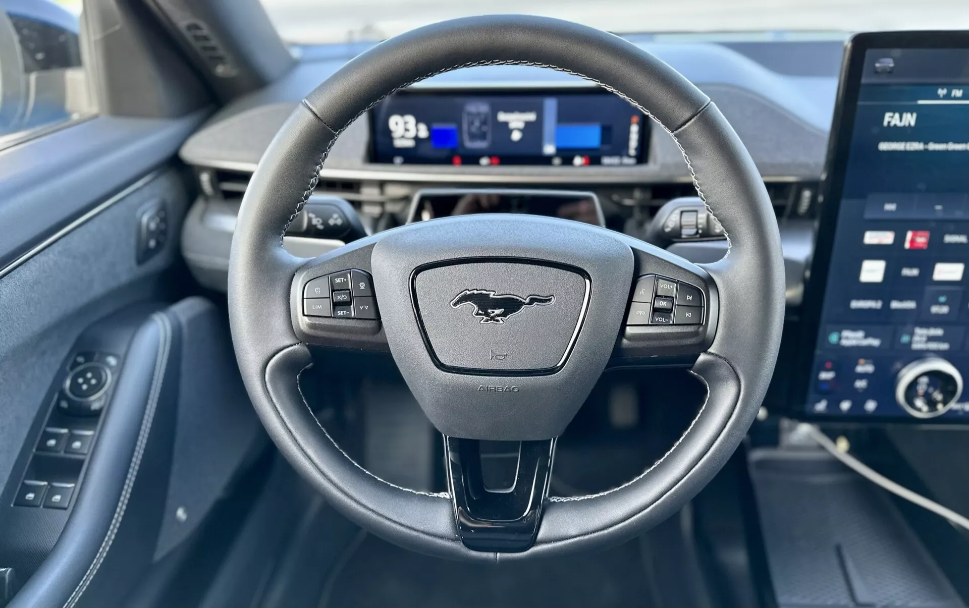 Notranji pogled Forda Mustang-Mach-E 2020 iz perspektive voznika, značilnosti volana s tremi kraki z gumbi za nadzor, digitalnega instrumentnega sklopa in velikega zaslona na dotik za infotainment