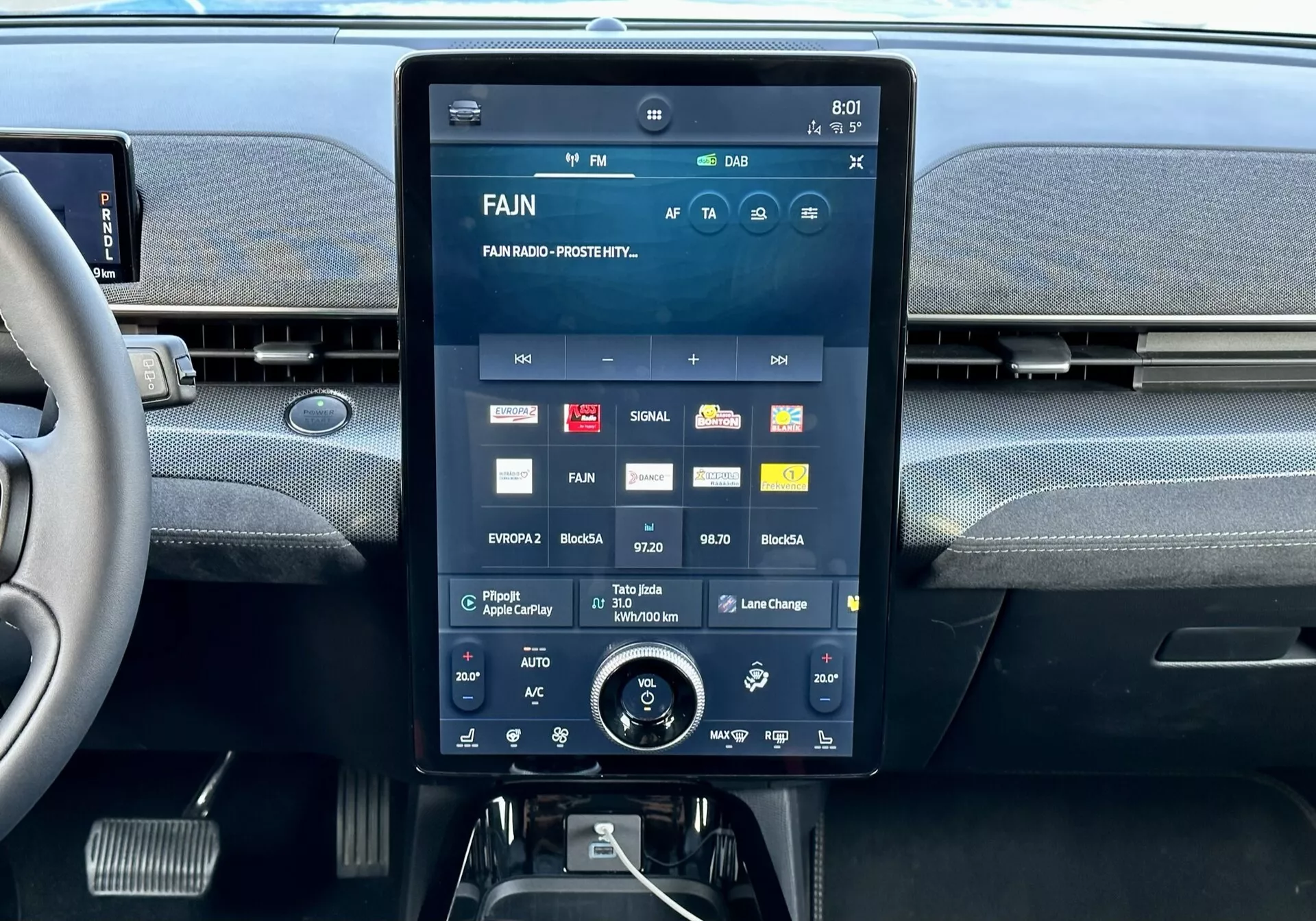 Notranja sredinska konzola Ford Mustang Mach-E 2020 z velikim zaslonom na dotik, ki prikazuje multimedijski vmesnik z aplikacijami in nastavitvami, vgrajenimi zračniki zgoraj in dodatnim rotacijskim gumbom za nadzor klime spodaj.