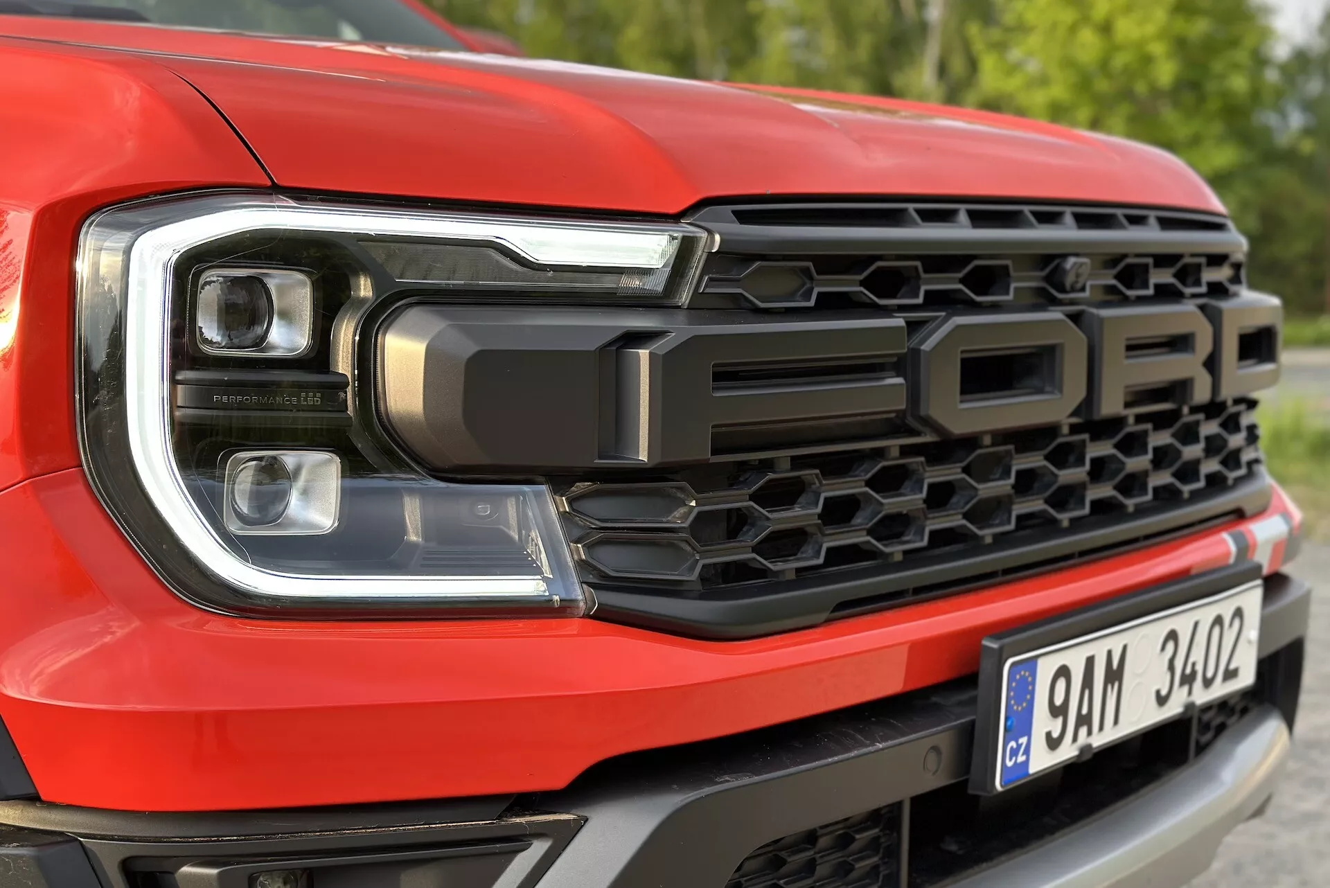Podrobnost sprednje leve strani Ford Rangerja 2022, poudarja dizajn LED žarometov in vzorec rešetke v slogu satovja, z napisom 'FORD'