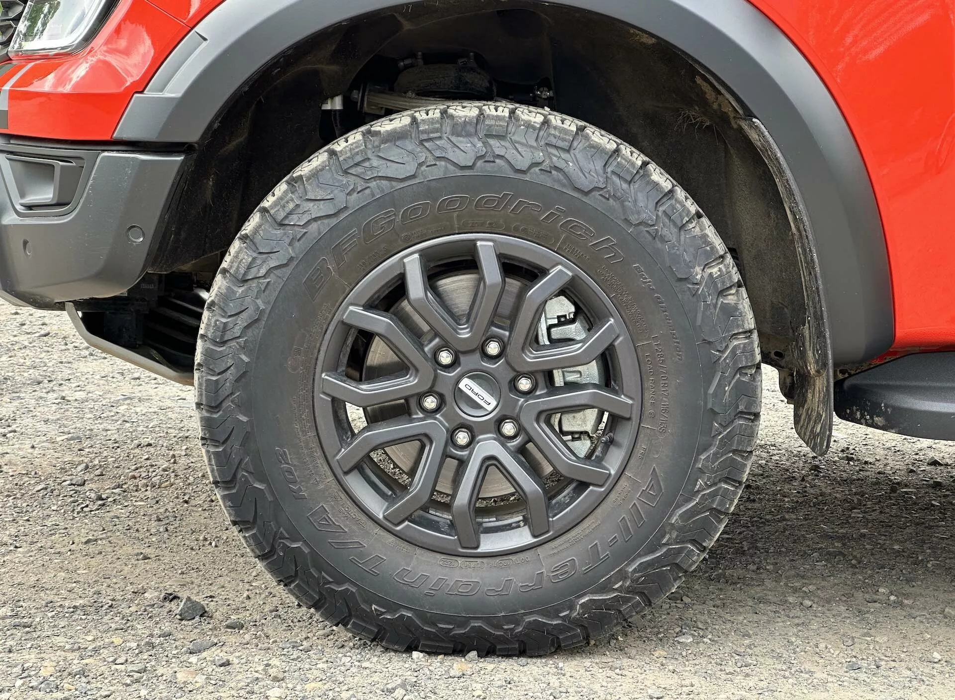 Podroben pogled na kolo Ford Rangerja 2022, ki prikazuje zasnovo z večkrakimi platišči iz zlitine, profil pnevmatike za vse terene in del blatnika z vidno svetlo višino podvozja