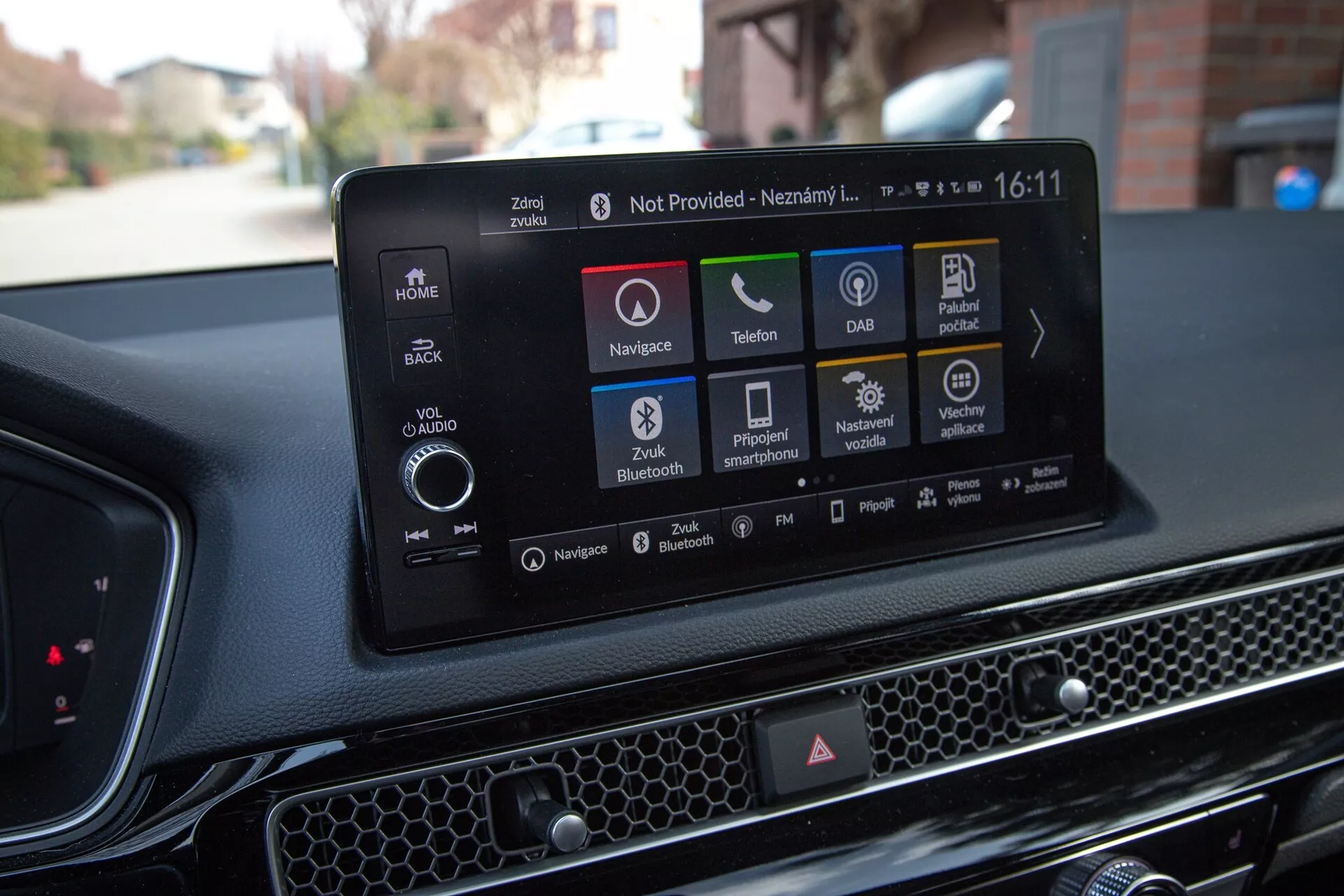 Notranjost Honda Civic 2022 prikazuje sodoben zaslon na dotik z navigacijo, ikonami za predvajanje zvoka in medijev, povezljivostjo s telefonom, DAB, informacijami o stanju avtomobila, možnostmi Bluetooth in nastavitvami vozila, proti teksturirani armaturni plošči s satovjem.