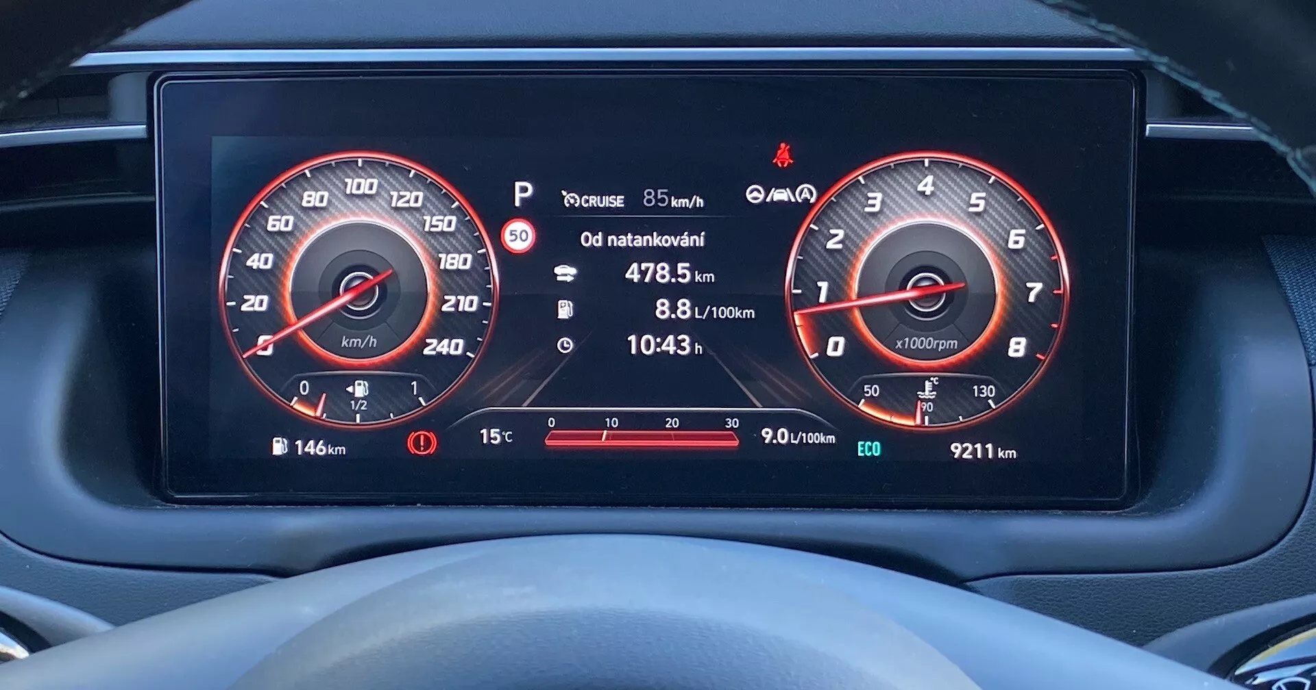 Povečani posnetek digitalne armaturne plošče v Hyundai Tucson 2020 iz voznikove perspektive, s prikazom visoko ločljivih zaslonov merilnika hitrosti (do 260 km/h) in merilnika vrtljajev (do 7000 vrt/min), kazala goriva, informacij o poti, obvestil o tlaku v pnevmatikah, zunanje temperature in različnih opozorilnih ikon.