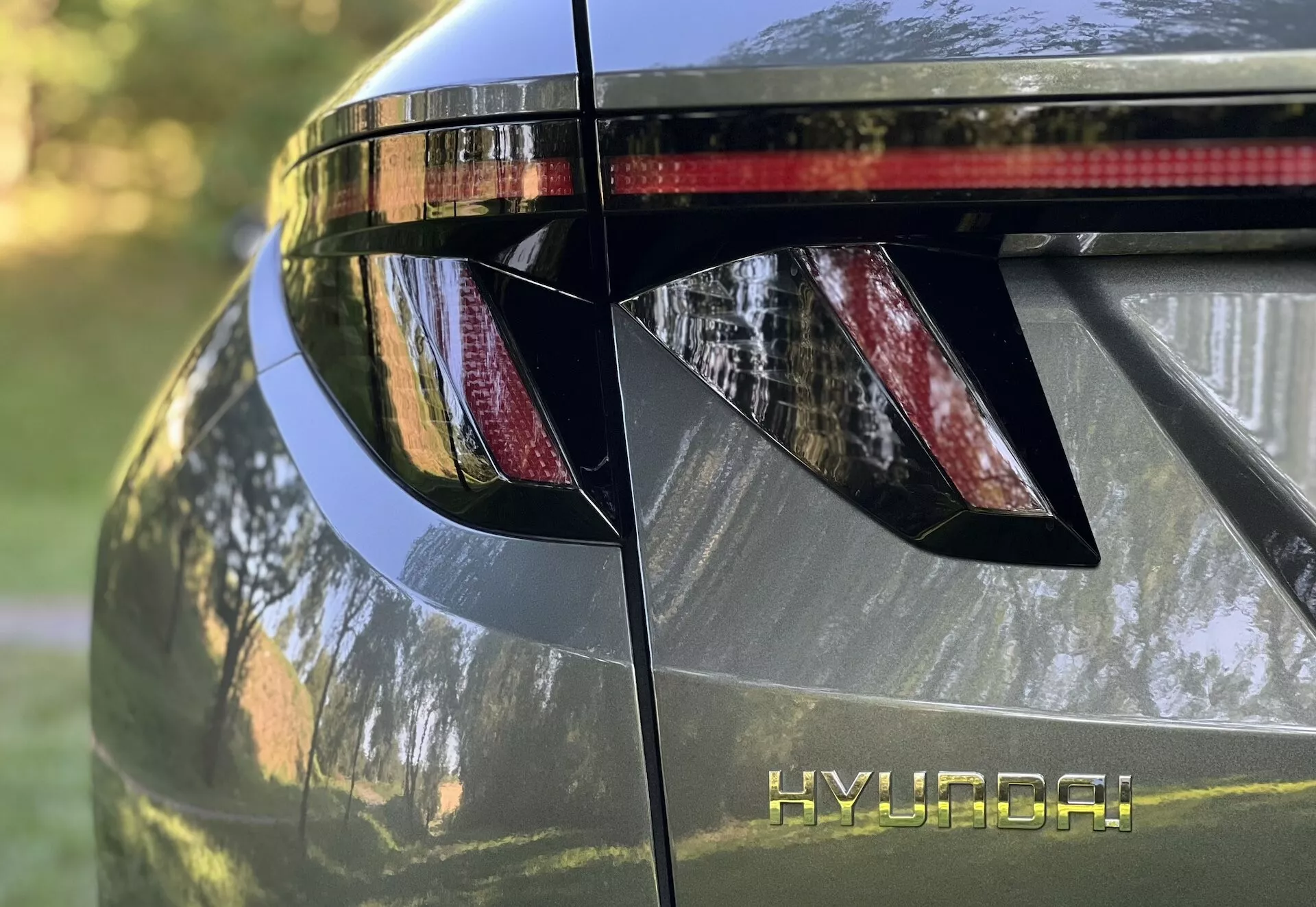 Približan pogled na zadnji del Hyundai Tucsona 2020, ki prikazuje kotne LED zadnje luči, blagovno znamko HYUNDAI, integrirani zadnji spojler z zavorno lučjo in sijajno kovinsko končno obdelavo
