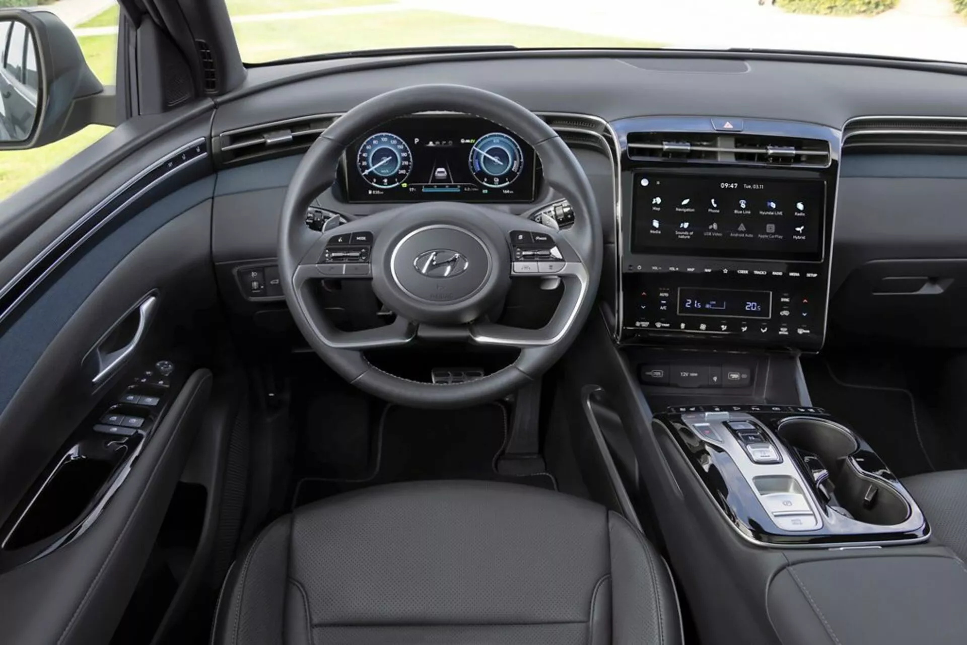 Notranjost Hyundai Tucson 2020 z vidika voznika, poudarjanje armaturne plošče, večfunkcijskega volana z logotipom Hyundai, popolnoma digitalnega instrumentnega sklopa, vertikalnega zaslona infotainment sistema, minimalističnih kontrolnih elementov na sredinski konzoli, elektronskega izbirnika prestav, usnjene oblazinjenje in sofisticirane monokromatske barvne sheme