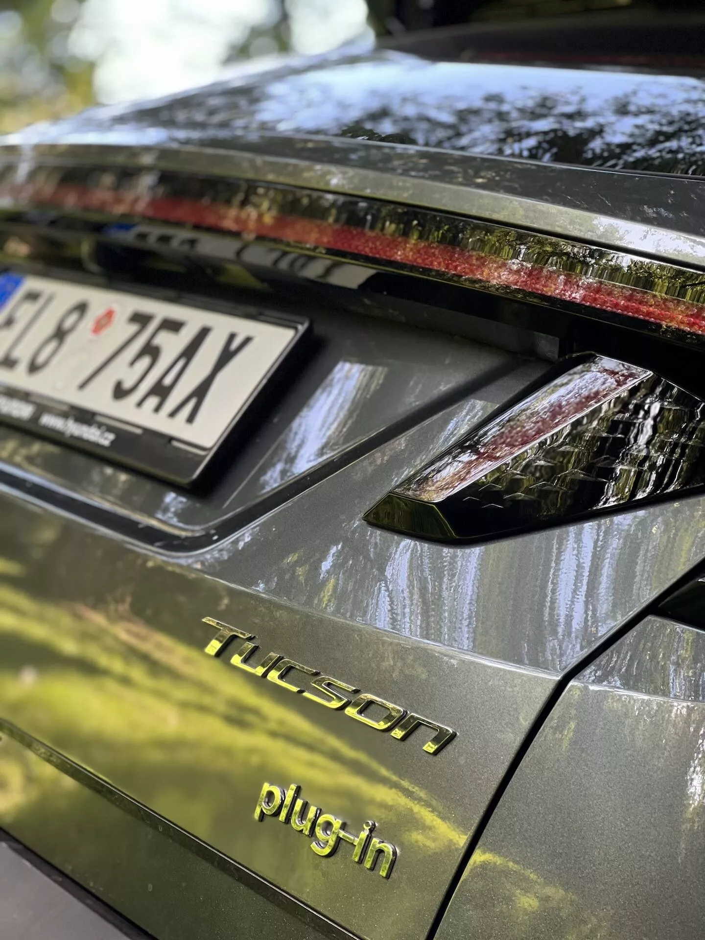 Podroben pogled na zadnji del Hyundai Tucson 2020 plug-in hibrida, vključno s pokrovom prtljažnika, zadnjo svetlobno enoto z LED lučmi, temno sijajno površino in podrobnostmi, ki kažejo na parkiranje na prostem