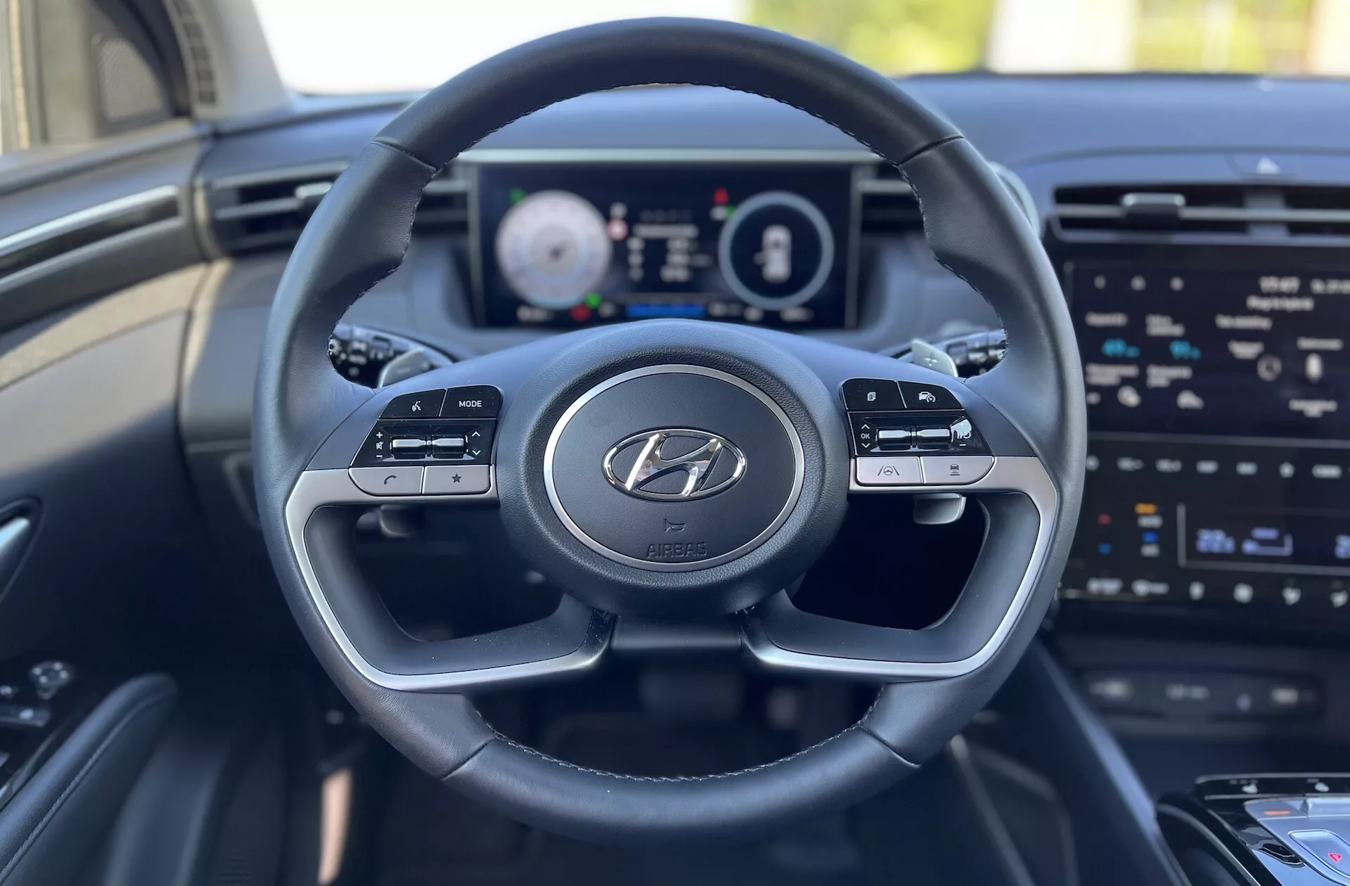 Notranji pogled Hyundai Tucson 2020 iz perspektive voznikovega sedeža, ki prikazuje volan z logotipom Hyundai, digitalni instrumentni zaslon in zaslon za informacijsko-zabavni sistem