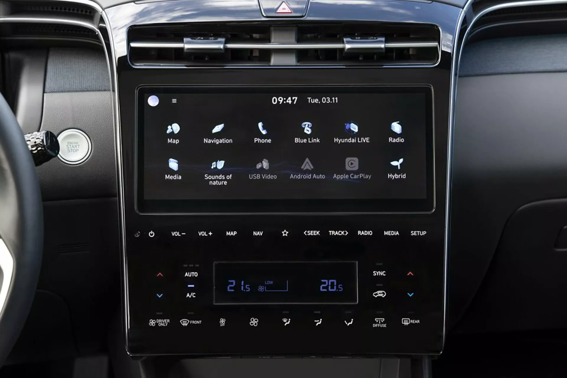 Notranjost Hyundai Tucson 2020 z modernim zaslonom na dotik infotainment sistemom z Android Auto in Apple CarPlay, samodejnim dvoconskim sistemom za nadzor klime nastavljenim na 21 stopinj Celzija in indikatorji hibridnega vozila
