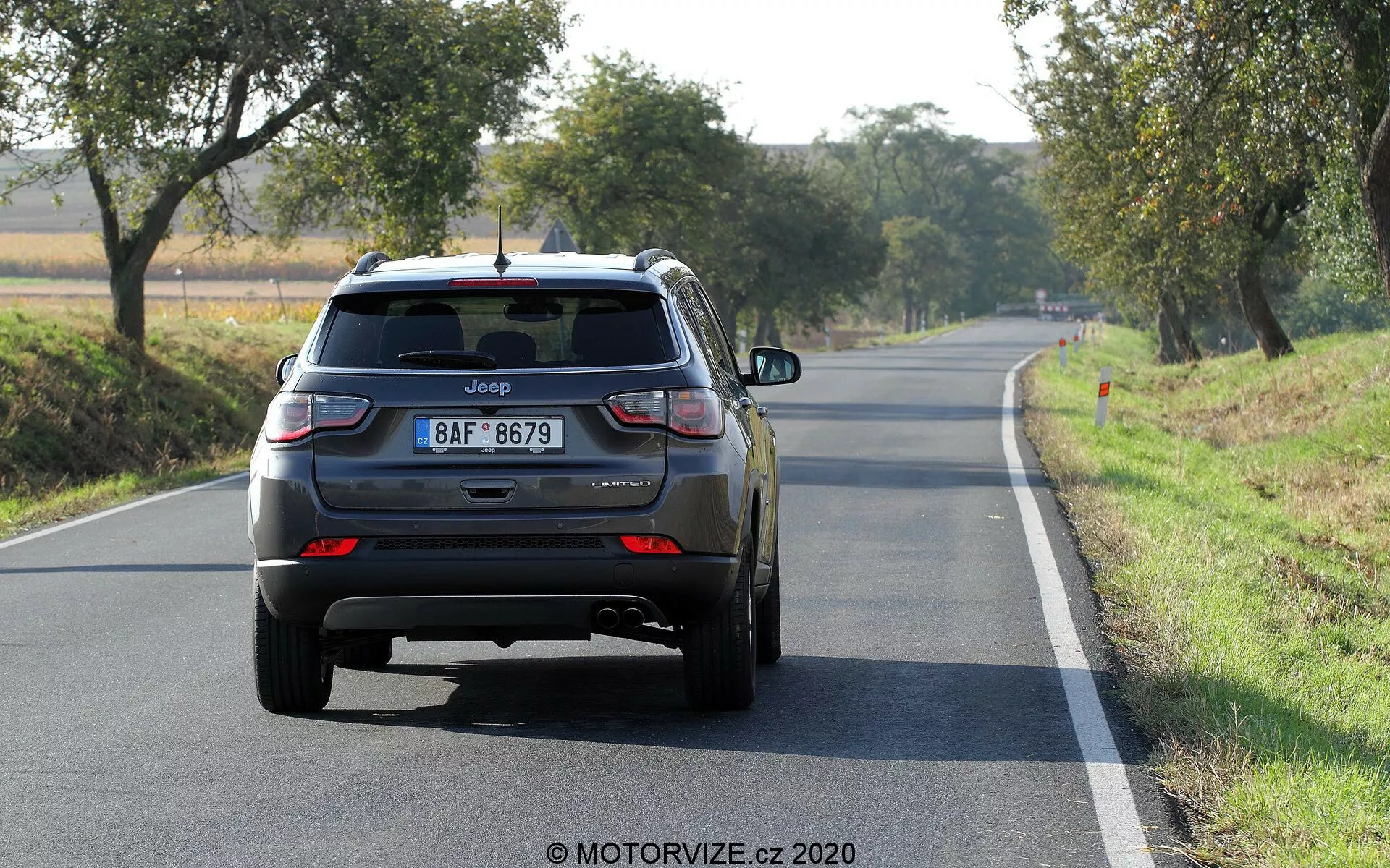 Pogled od zadaj na Jeep Compass SUV 2017 na dvopasovni cesti v dnevni svetlobi, vidna znamka, ime modela, evropska registrska tablica, LED zadnje luči, zaprt prtljažnik z zadnjim brisalcem vetrobranskega stekla, tretja zavorna luč na zadnjem spojlerju, zadnji odbijač z odsevniki, dvojni izpušni cevi na levi strani, zadnja aluminijasta kolesa, dodatni znaki, ki verjetno označujejo raven opreme ali pogona.