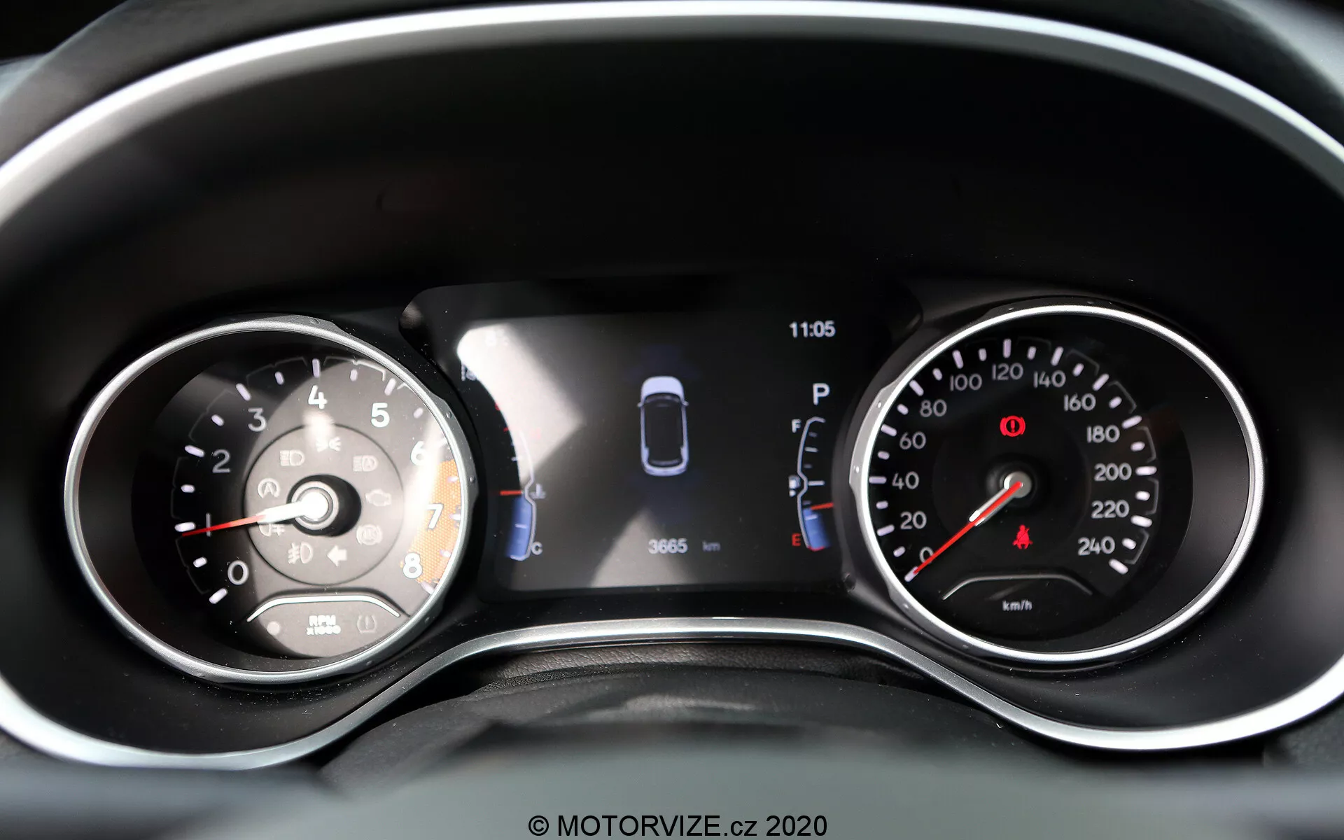 Bližnji pogled na instrumentno ploščo Jeep Compass 2017 z združeno analogno in digitalno zaslonom. Na levi strani je analogen merilnik hitrosti, označen do 260, z iglo, ki kaže tik nad 0. Osrednji digitalni zaslon prikazuje grafični prikaz avtomobila s senzorji in dvema odprtima vratoma, kar označuje pomoč pri parkiranju in stanje vozila. Ura kaže 11:05. Na desni strani je analogen merilnik vrtljajev z rdečim območjem, ki se začne pred 7, označen do 8 (povečanje za 1.000 vrt/min). Vidne so dodatne opozorilne lučke in ikone, kar naredi to dobro osvetljeno in jasno predstavitev sodobnih in tradicionalnih odčitkov vozila ter tehnologij za pomoč vozniku.