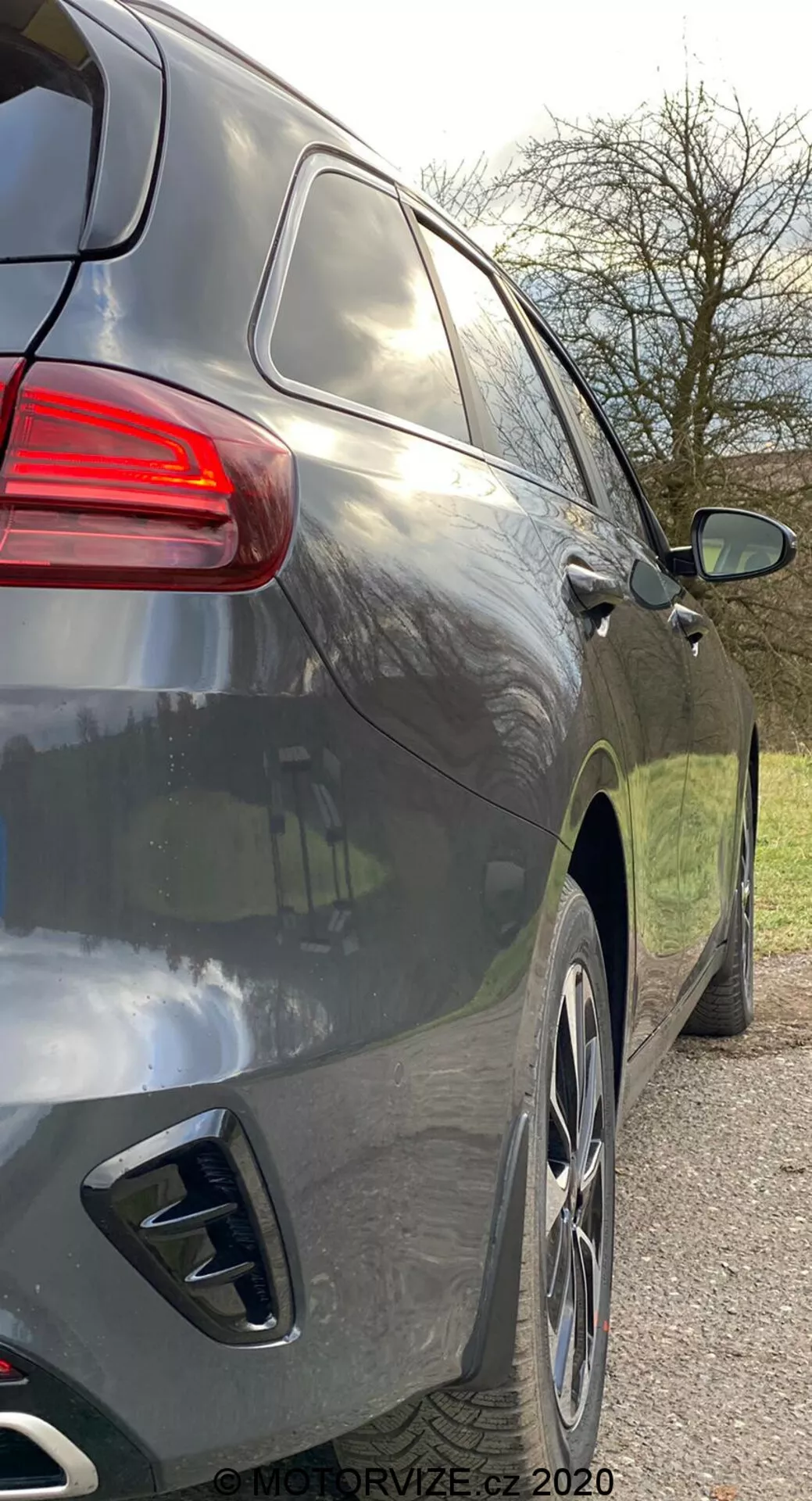 Podroben pogled z rahlo zadnjega kota na desni stranski pogled sodobnega SUV-ja, ki prikazuje zadnji del in stranski profil od zadnje kljuke vrat do zadnjih luči, s gladkimi aerodinamičnimi linijami, temno kovinsko barvo, velikimi aluminijastimi platišči, dvojnimi izpušnimi konci, zatemnjenimi okni in sodobno oblikovanimi zadnjimi lučmi.