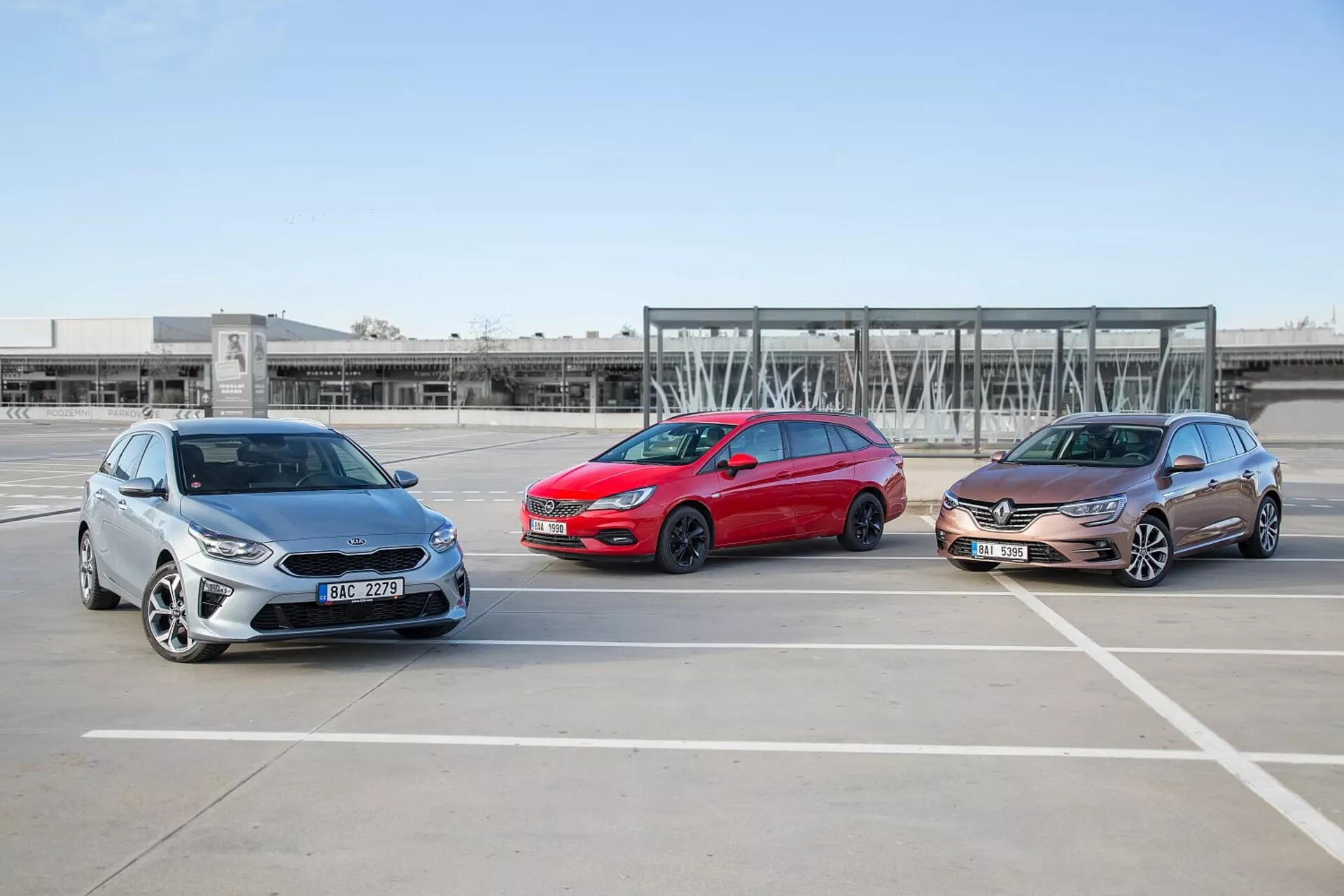 Trije modeli Kia Ceed 2009, postavljeni v zamaknjeni formaciji na praznem parkirišču, prikazujejo svoje sprednje in stranske profile v jasnem vremenu