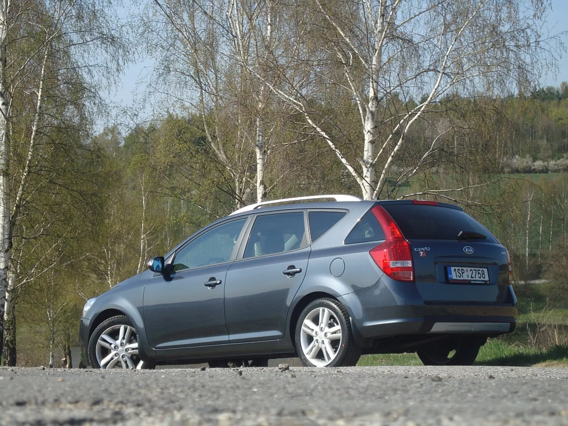 Siva karavanska Kia Ceed iz leta 2009, ki prikazuje stranski in zadnji dizajn, s poudarki na aerodinamični liniji strehe, zadnjih lučeh in zadnjem oknu, parkirana na prostem