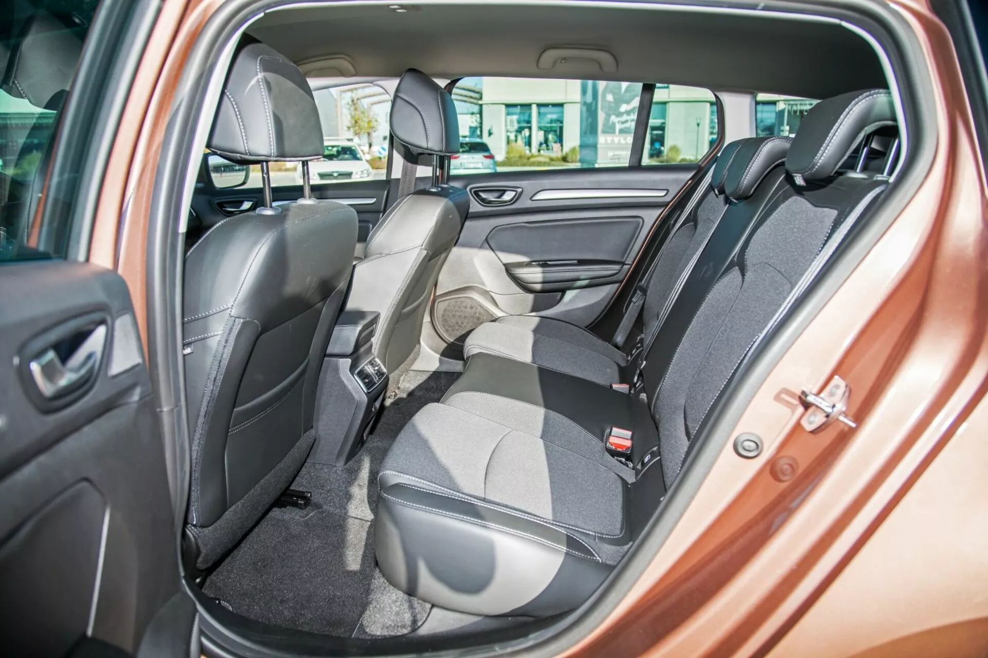Notranjost Kia Ceed 2009, ki prikazuje dvobarvno zadnjo klopno sedež s enim sedežem, zloženim naprej za tovor, varnostne pasove, naslone za glavo, kontrole električnih oken in zvočnik na vratih, poudarjajoč fleksibilno postavitev sedežev in luksuzno oblikovanje