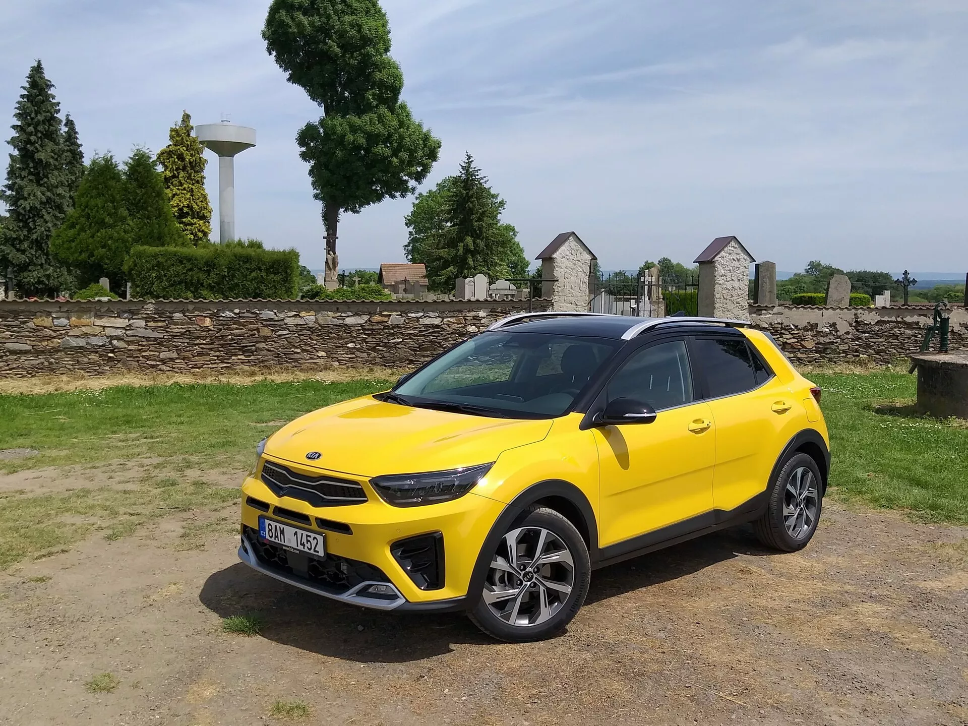 Kia Stonic 2017 v svetlo rumeni barvi, prikazuje svojo sprednjo rešetko, LED žaromete, športni sprednji odbijač in eleganten stranski profil z večkrakimi zlitinskimi kolesi in strešnimi nosilci, kar poudarja estetiko kompaktnega križanca in napredne oblikovalske značilnosti vozila.