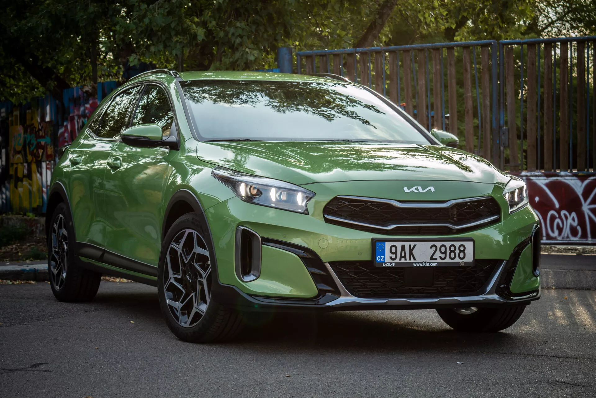 Zeleni Kia Xceed 2022, parkiran pod kotom, ki prikazuje svoj tristranski sprednji pogled z LED žarometi in športnimi zlitinskimi kolesi v mestnem okolju