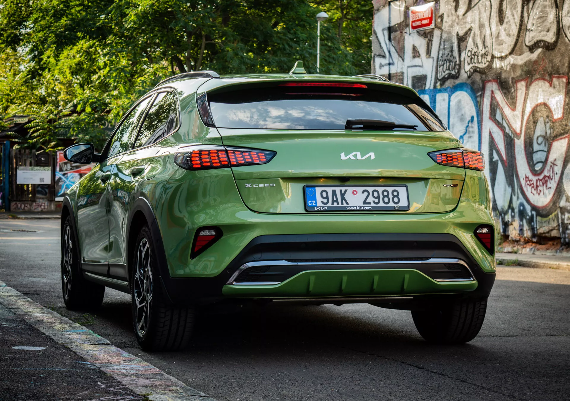 Zadnji pogled na zeleni crossover/SUV Kia XCeed letnik 2022, ki prikazuje znamko, dizajn LED zadnjih luči, namestitev registrske tablice, estetiko spodnjega odbijača in sijajni zaključek na mestni ulici.