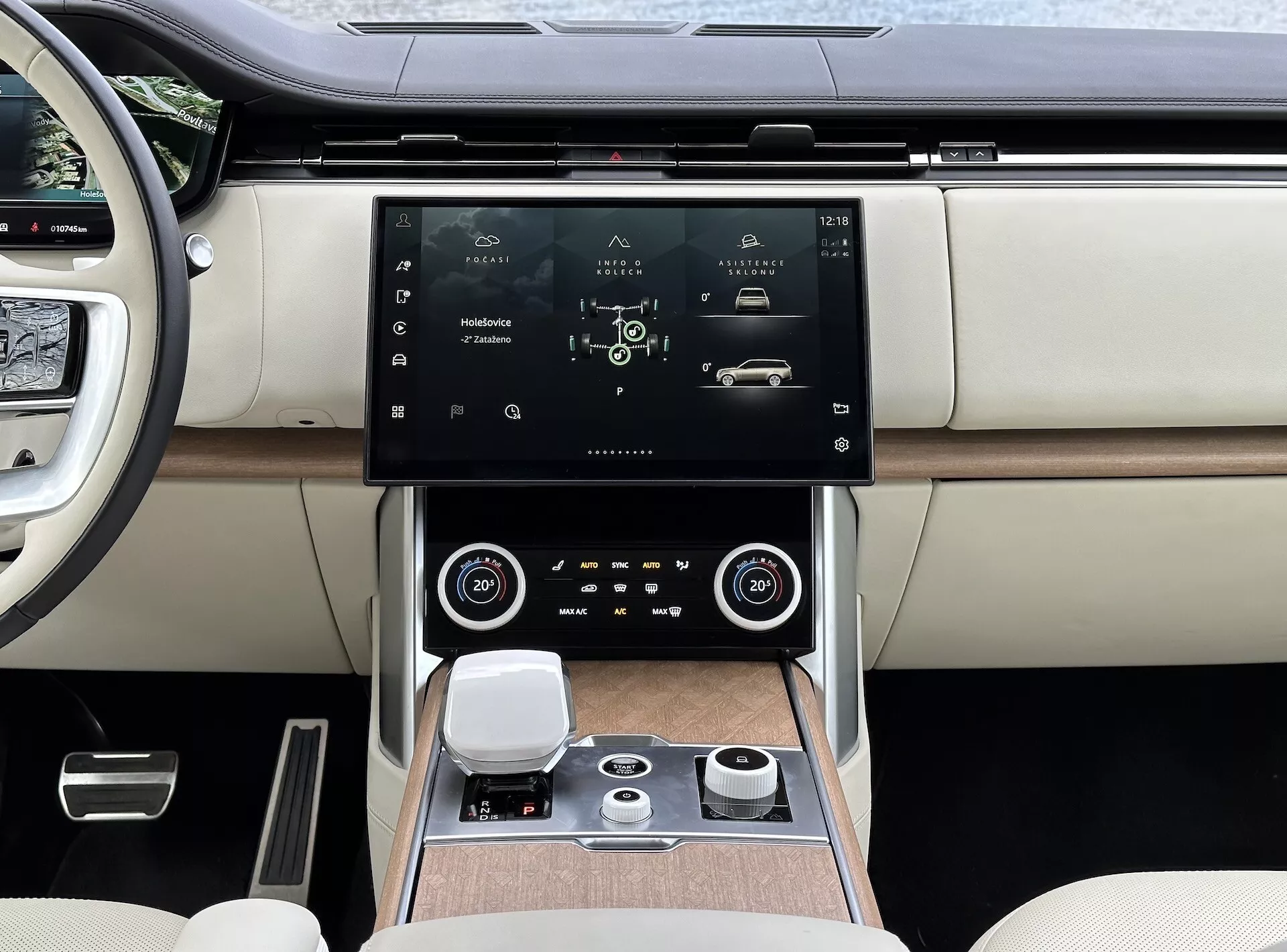 Land Rover Range Rover 2021 z moderno notranjostjo, osredotočeno na sredinsko konzolo in sistem za infotainment z visokoresolucijskim zaslonom na dotik, zračnimi režami s kromiranimi poudarki, dvopodročnim klimatskim nadzorom, rotacijskim upravljalnim gumbom za navigacijo sistema in luksuznimi sedeži iz dvobarvnega usnja z detajli iz lesa.