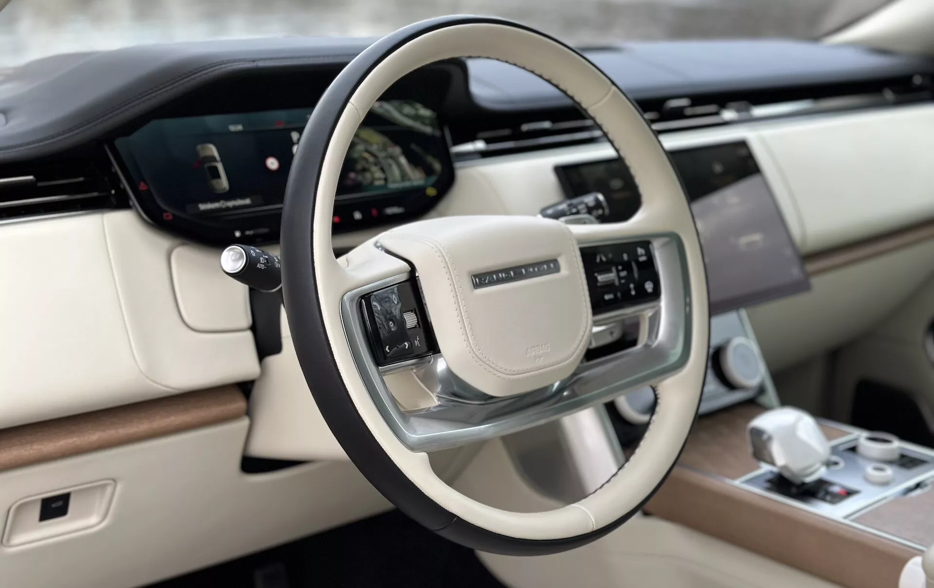 Notranjost vozila Land Rover Range Rover 2021 s poudarkom na luksuznem usnjenem volanu z naprednimi kontrolnimi gumbi in delom digitalne armaturne plošče iz perspektive voznika