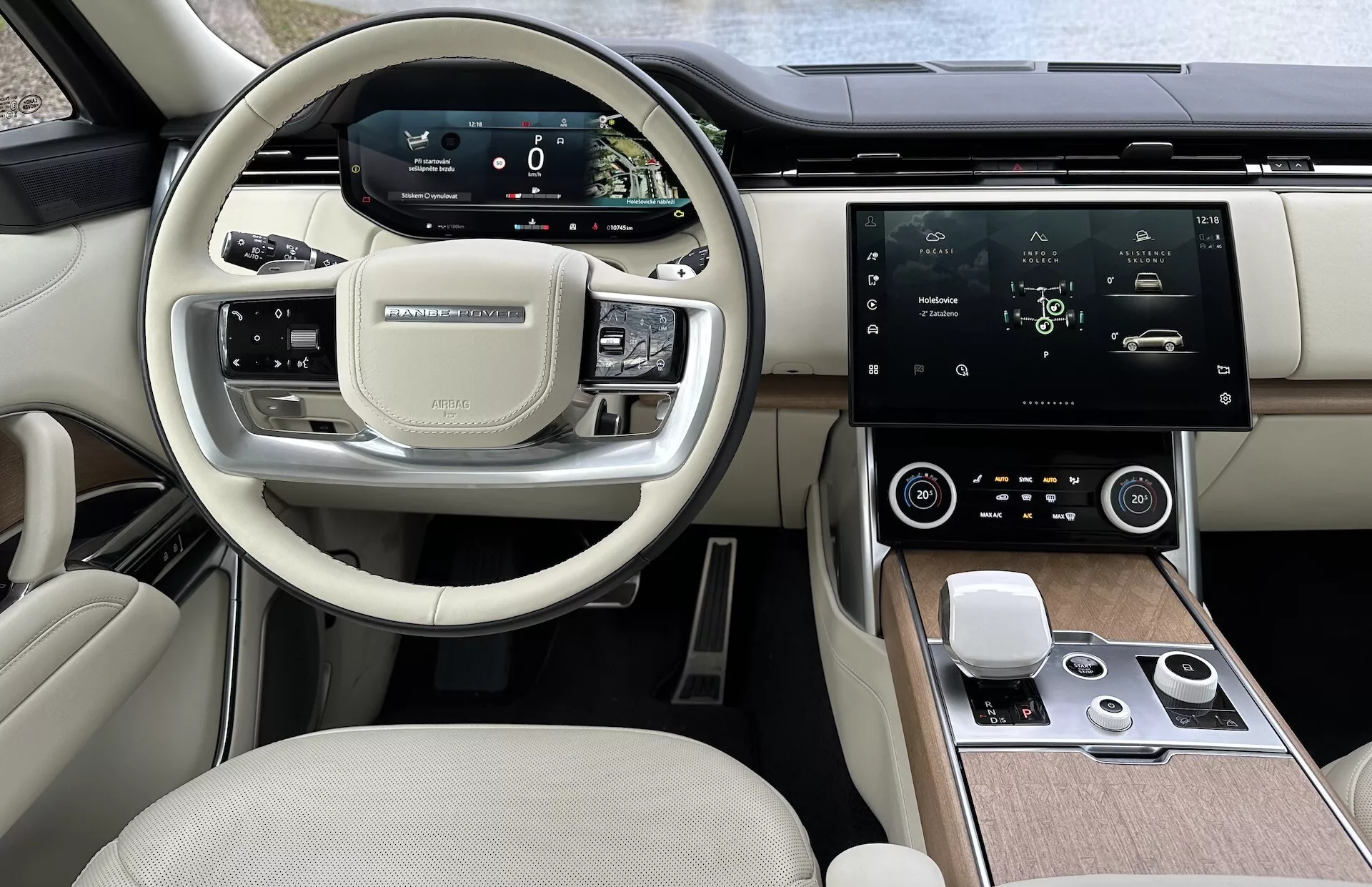 Notranjost Land Rover Range Rover 2021, ki prikazuje sodoben volan z večnamenskimi gumbi, digitalno instrumentno ploščo, velik osrednji zaslon na dotik za informacije in zabavo, avtomatsko klimatsko napravo in dvobarvno zasnovo kabine visokega razreda