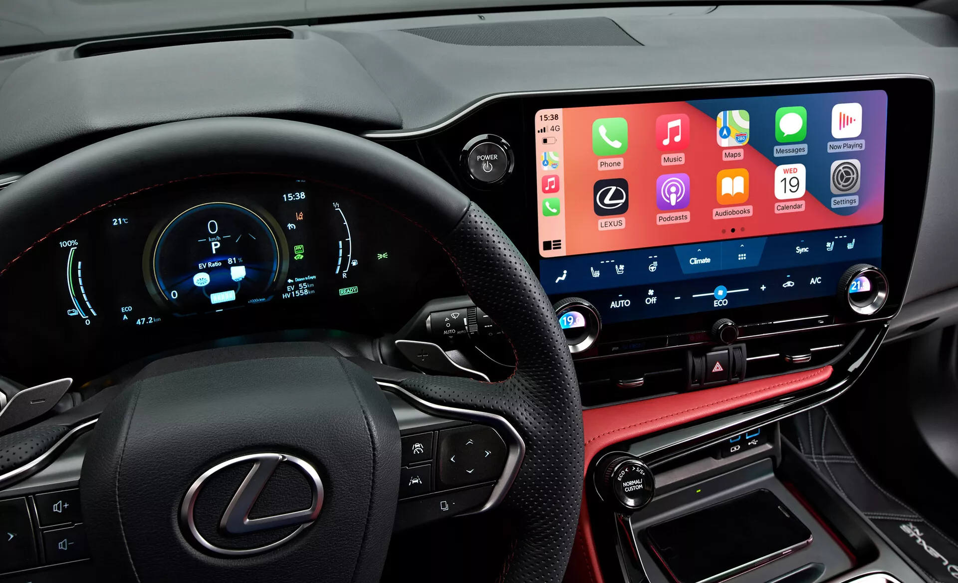 Notranji pogled na Lexus NX 2021, ki iz voznikove perspektive prikazuje moderen, tehnološko napreden armaturni pult. Na levi je delno viden volan s logotipom Lexus in večfunkcijskimi gumbi. Digitalni instrumentni zaslon prikazuje hitrost, vrtljaje in druge metrike v modri in beli barvi. Na sredini je širok zaslon na dotik infotainment sistema, ki integrira funkcije pametnega telefona. Pod njim so gumbi in gumbi za upravljanje s klimatsko napravo z digitalnimi prikazi temperature. Spodnji del vključuje konzolo s šivanjem iz usnja, prestavno ročico in povezovalne vhode, ki odražajo luksuzne zaključke vozila.