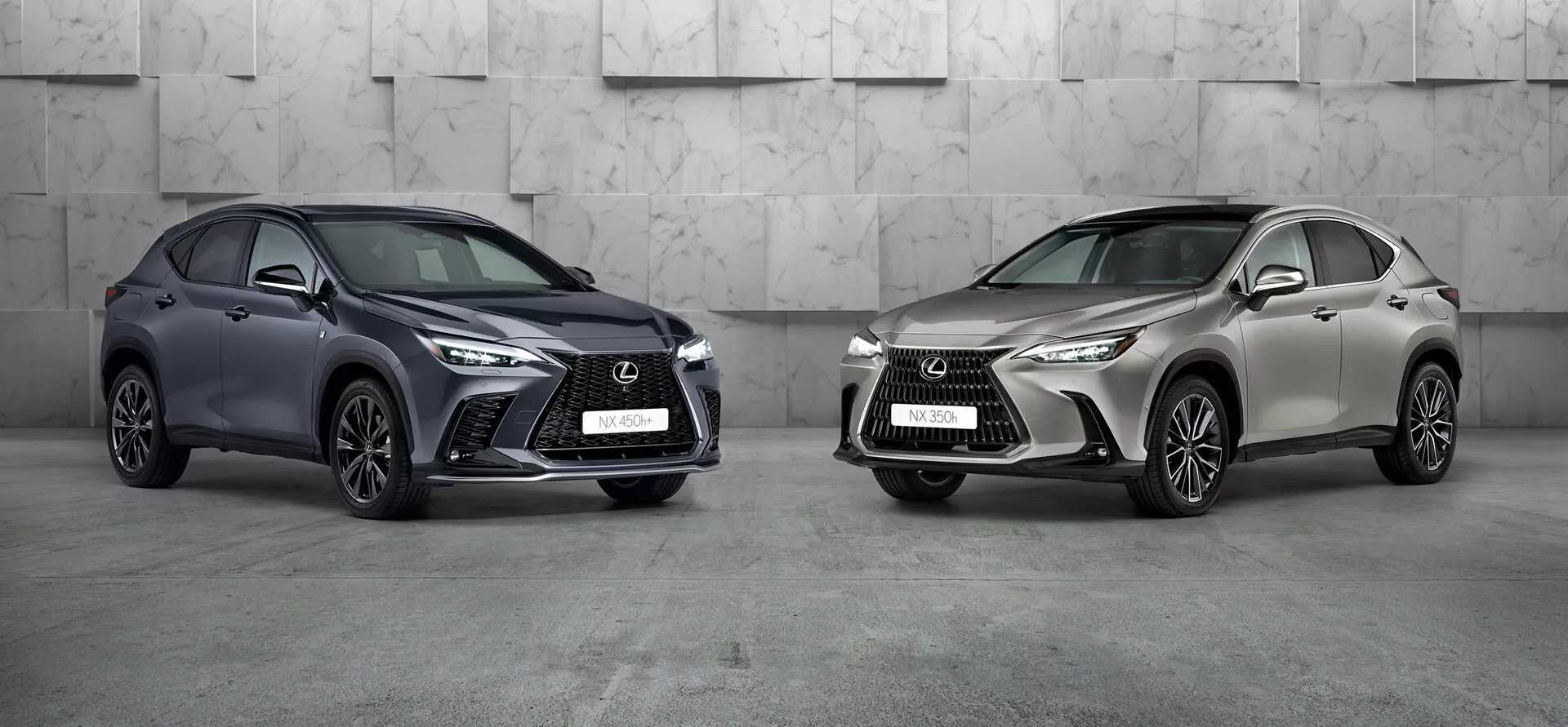 Slika prikazuje dva avtomobila Lexus NX 2021 v profesionalnem studijskem okolju. Avtomobil na levi, temno obarvan kompaktni SUV z značilno agresivno sprednjo rešetko, ostrimi LED žarometi in velikimi vstopnimi odprtinami, je nagnjen, da pokaže svoje levo sprednje in bočno stran. Kolesa so obrnjena proti kameri, kar poudarja oblikovanje platišč. Avtomobil na desni, v svetlem kovinskem odtenku, je prav tako nagnjen, vendar v levo, s podobnim oblikovalskim jezikom, vendar z drugačnim slogom platišč. Obe luksuzni SUV-ji, ki se v okvirju pojavljata izrazito, prikazujeta napreden dizajn in možne sodobne tehnologije.