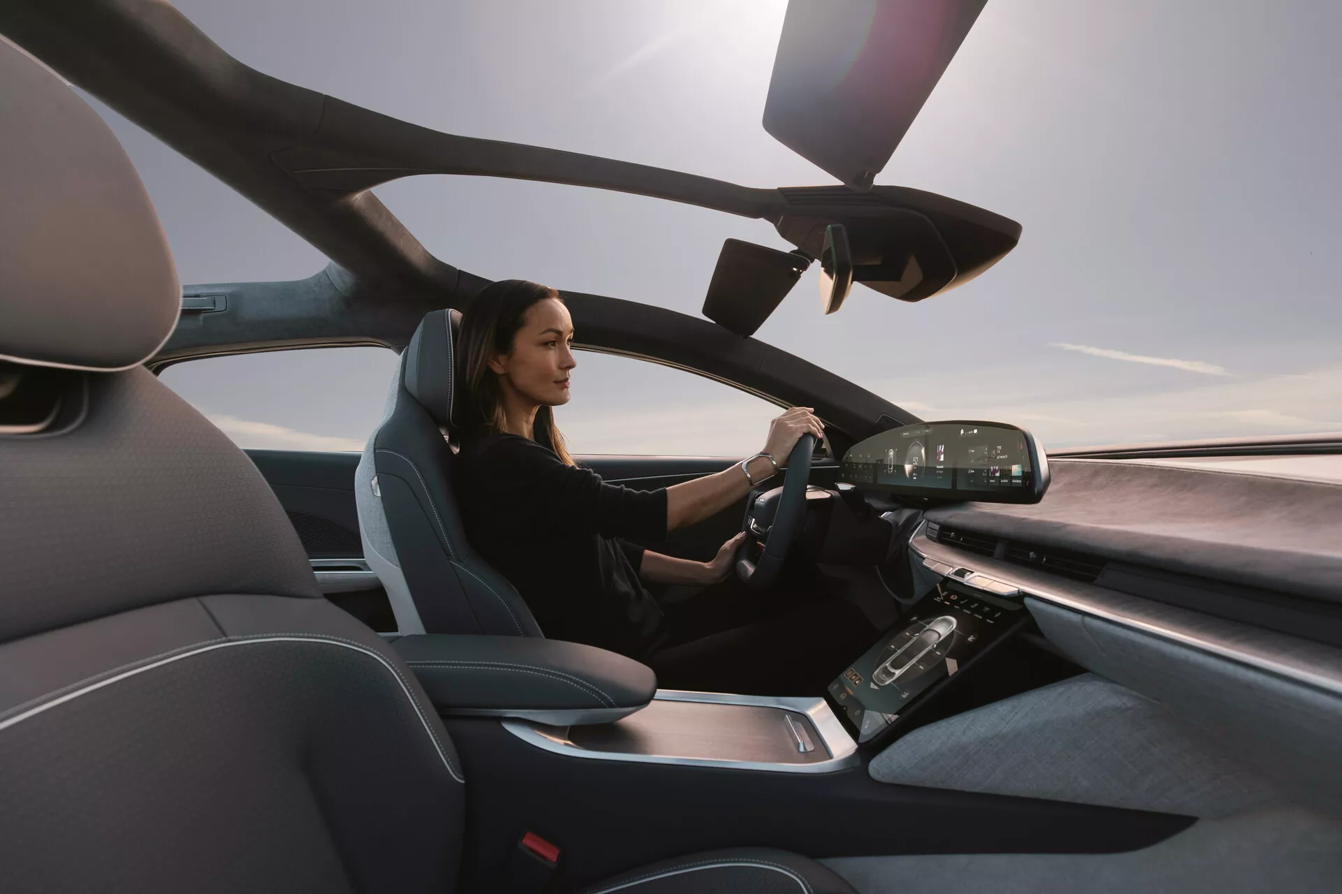 Pogled na notranjost Lucid Air 2022 s sovoznikove strani, ki prikazuje sodoben voznikov sedež in napredno armaturno ploščo z digitalnimi zasloni in zasloni na dotik, poudarja luksuzen in tehnološko napreden dizajn