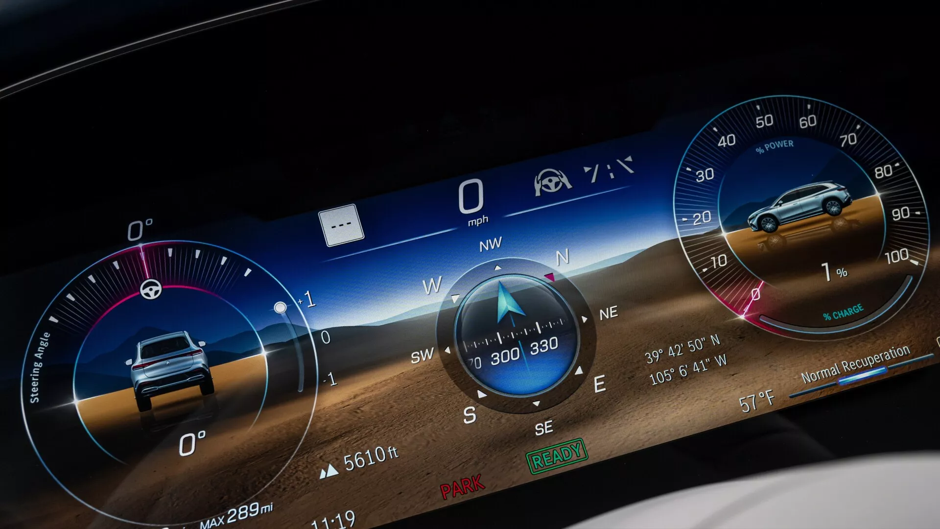 Povečana slika digitalne armaturne plošče Mercedes EQS SUV 2022, z širokozaslonskim grafičnim uporabniškim vmesnikom, ki prikazuje različne meritve, kot so merilnik hitrosti pri 0 mph, kompas, ki kaže proti severozahodu, verjetno merilnik vrtljajev, informacije o prevoženih kilometrih, kot je 'Max 289m', in ikone za opomnik varnostnega pasu ter pomoč voznika. Ozadje vključuje dinamično pokrajino za vizualno privlačnost.