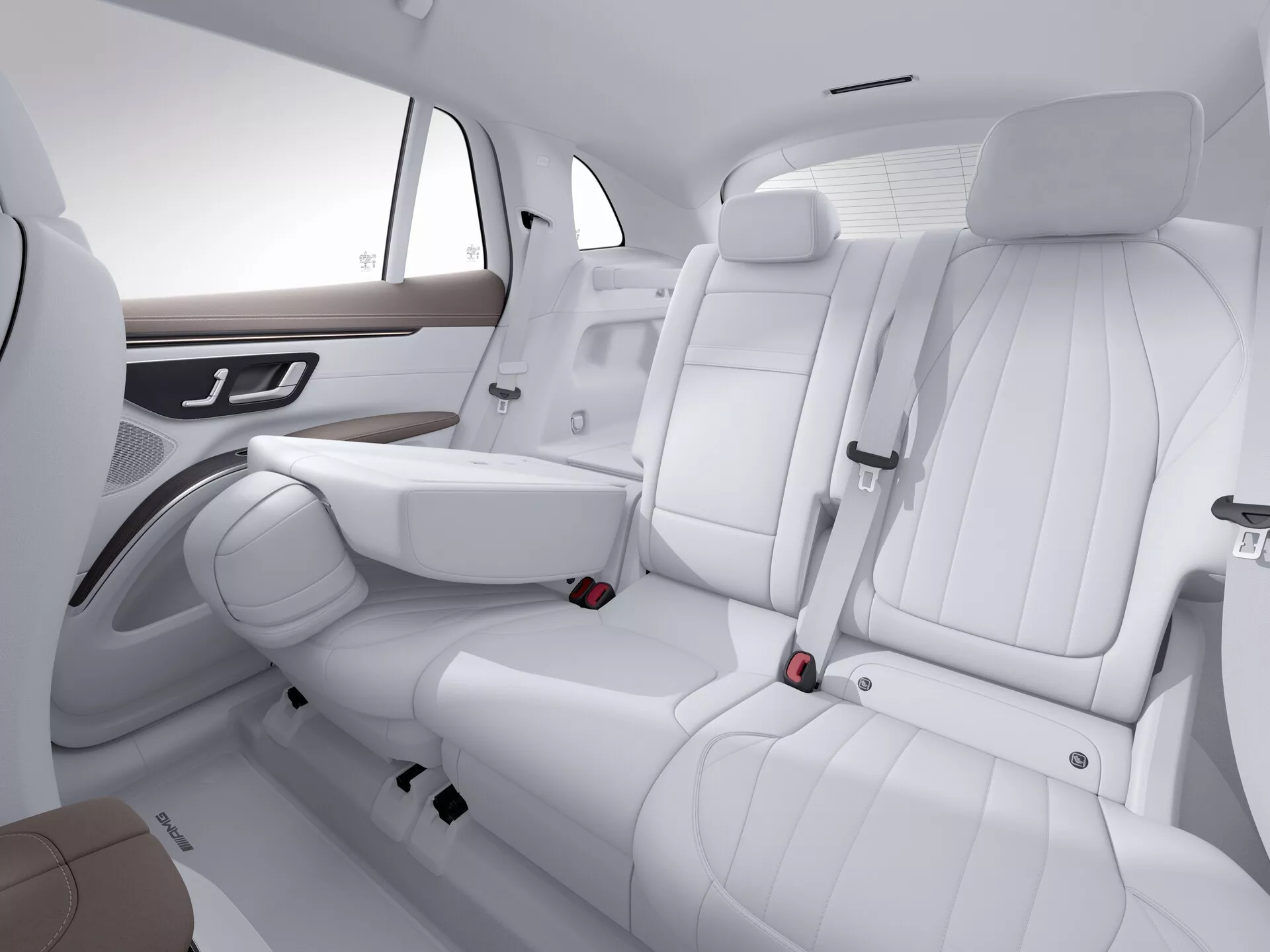 Notranjost Mercedes EQS SUV 2022, ki se osredotoča na zadnje sedeže iz desne sprednje perspektive. Trije sedeži iz belega usnja, z detajlnim šivanjem, imajo na sredinskem sedežu zložljiv naslon za roke. Vgrajeni nasloni za glavo in tritočkovni varnostni pasovi zagotavljajo varnost, medtem ko leseni okrasni elementi in kromirani ročaji na stranskih naslonih za roke poudarjajo luksuz. Minimalistična zasnova vratnih panelov in prostorna razporeditev povečujeta estetsko čistost. Študijska postavitev poudarja sodobno, urejeno in visokokakovostno notranjost avtomobila.