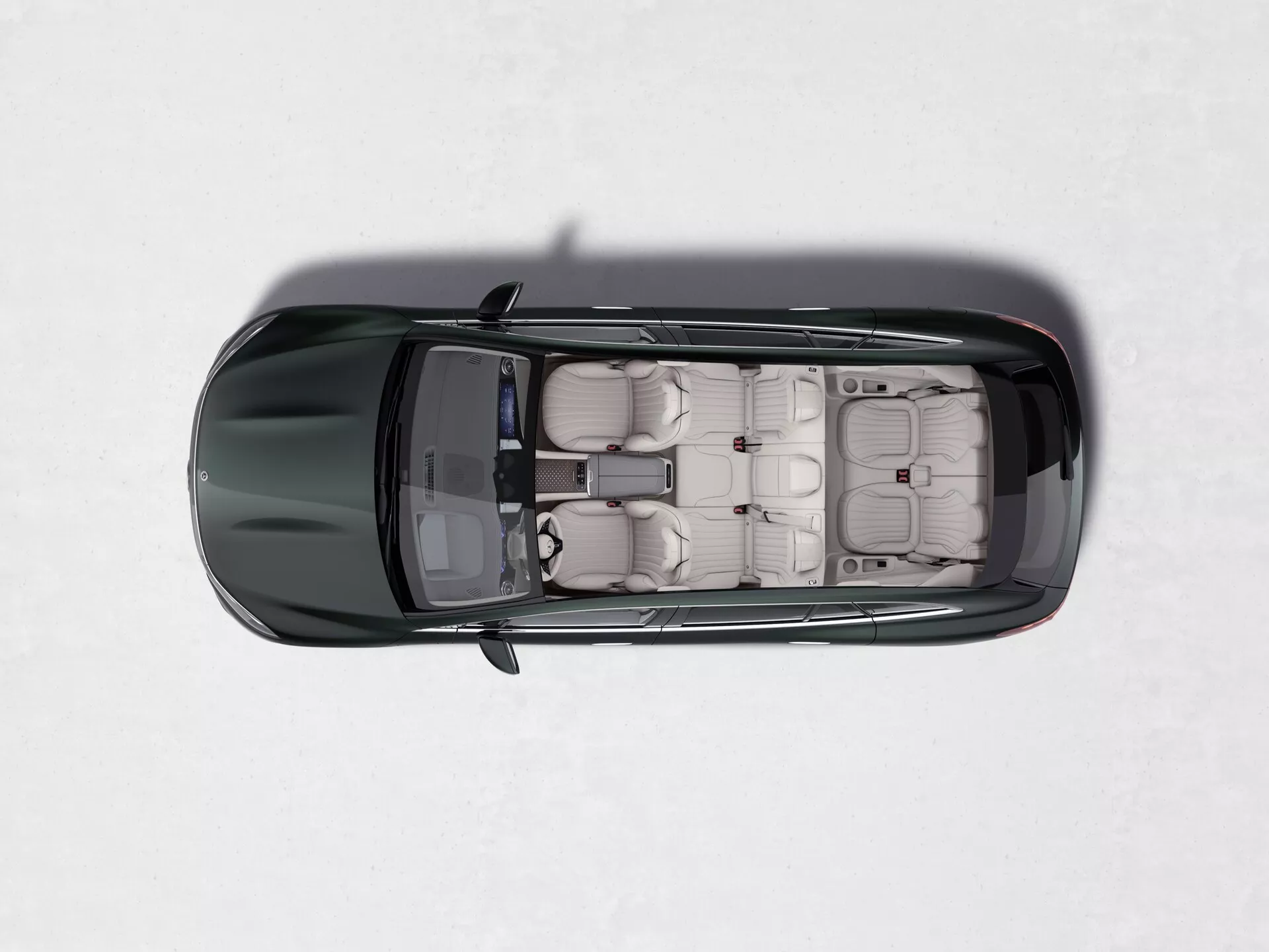 Pogled od zgoraj na Mercedes EQS SUV 2022 z njegovim strešnim oknom, svetlim usnjenim oblazinjenjem, posameznimi sedeži z vzglavniki, štirimi vrati s skritimi kljukami, svetlečim temnim lakom in kontrastnimi stranskimi ogledali na svetli, enotni površini.