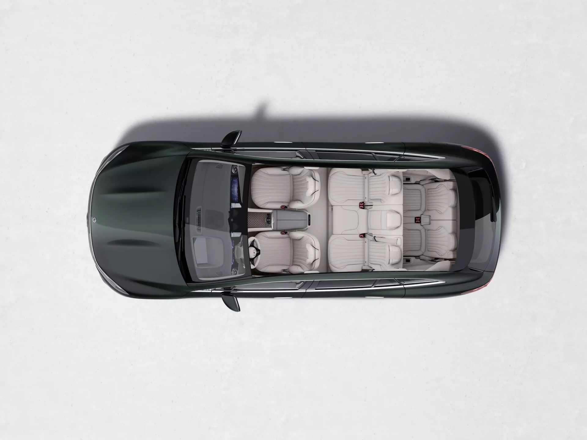 Pogled od zgoraj na temnobarvni Mercedes EQS-SUV 2022 na svetli, zasneženi površini. Slika prikazuje popolnoma odprto strešno okno, ki razkriva bežno ali rjavo usnjeno notranjost s tremi vrstami sedežev, poudarjajoč zmogljivost večjega potniškega vozila, verjetno SUV.