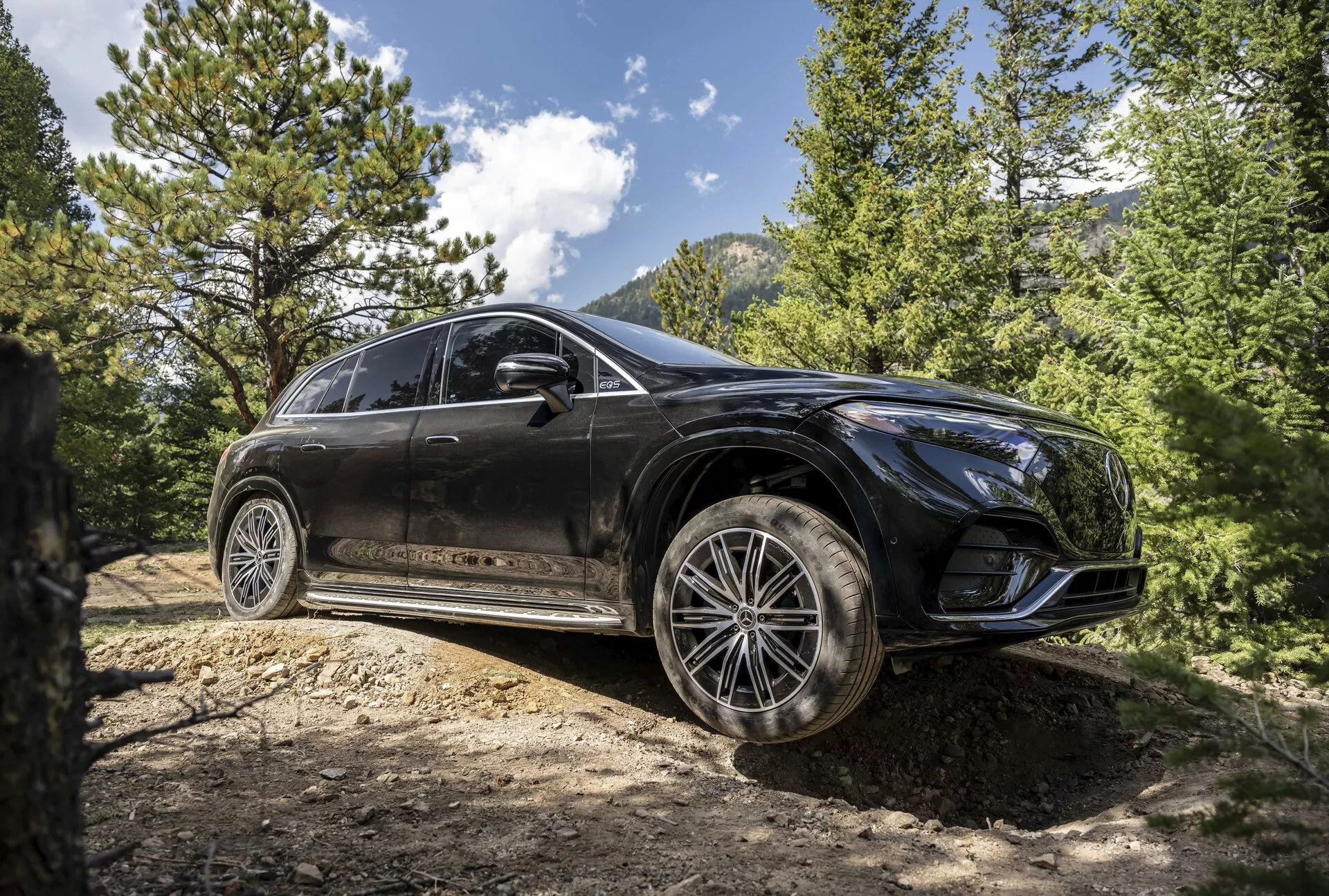 Spredaj trikovinski pogled na Mercedes EQS SUV 2022, ki prikazuje njegov eleganten dizajn, napredne LED žaromete, panoramsko streho in vrhunska aluminijasta platišča v prefinjenem mestnem okolju.