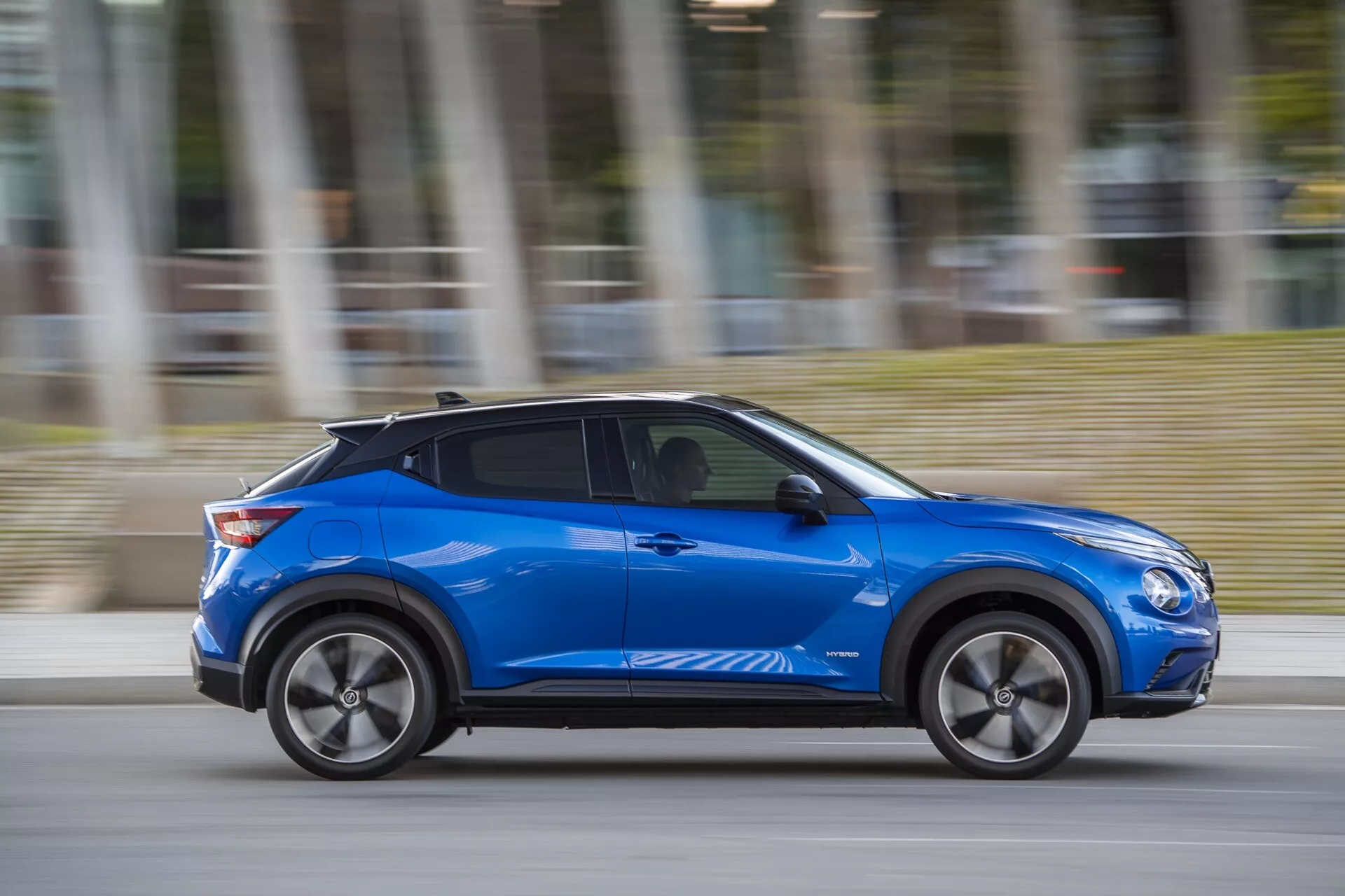 Nissan Juke (F16) iz leta 2019 v modri barvi, ki predstavlja sodobno oblikovanje in tehnološko vodene funkcije, kot so aerodinamične linije karoserije, platišča iz lahkih zlitin in potencialno brezključno vstopanje, dinamično gibanje z zameglitvijo gibanja v oblačen dan