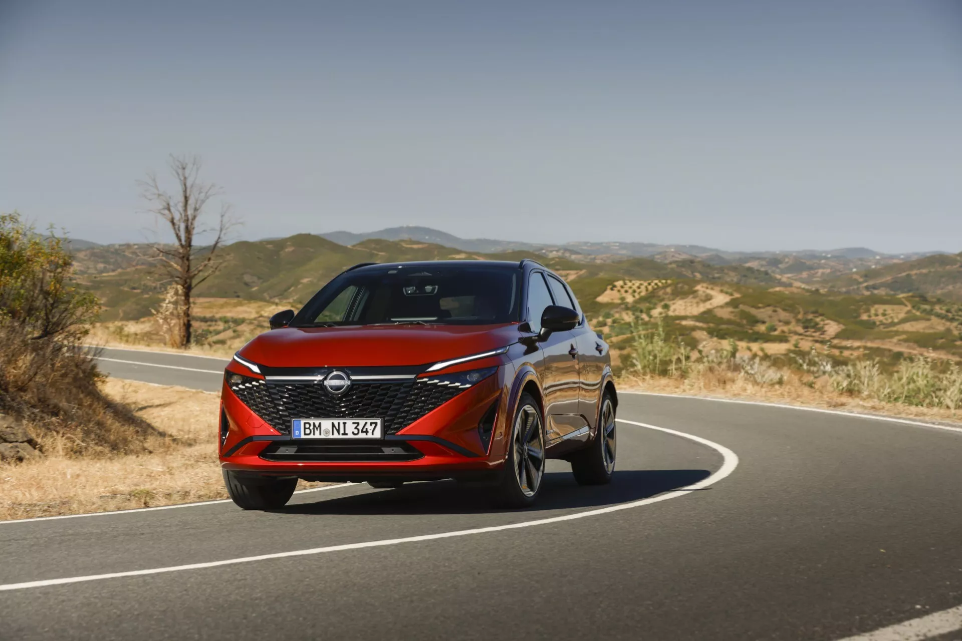 Sprednji pogled na Nissan Qashqai 2024 J12-facelift, ki prikazuje sodoben dizajn z elegantnimi LED žarometi, drzno sprednjo masko v obliki črke V-motion in dinamičnimi linijami, ki poudarjajo njegovo športno in prefinjeno estetiko.