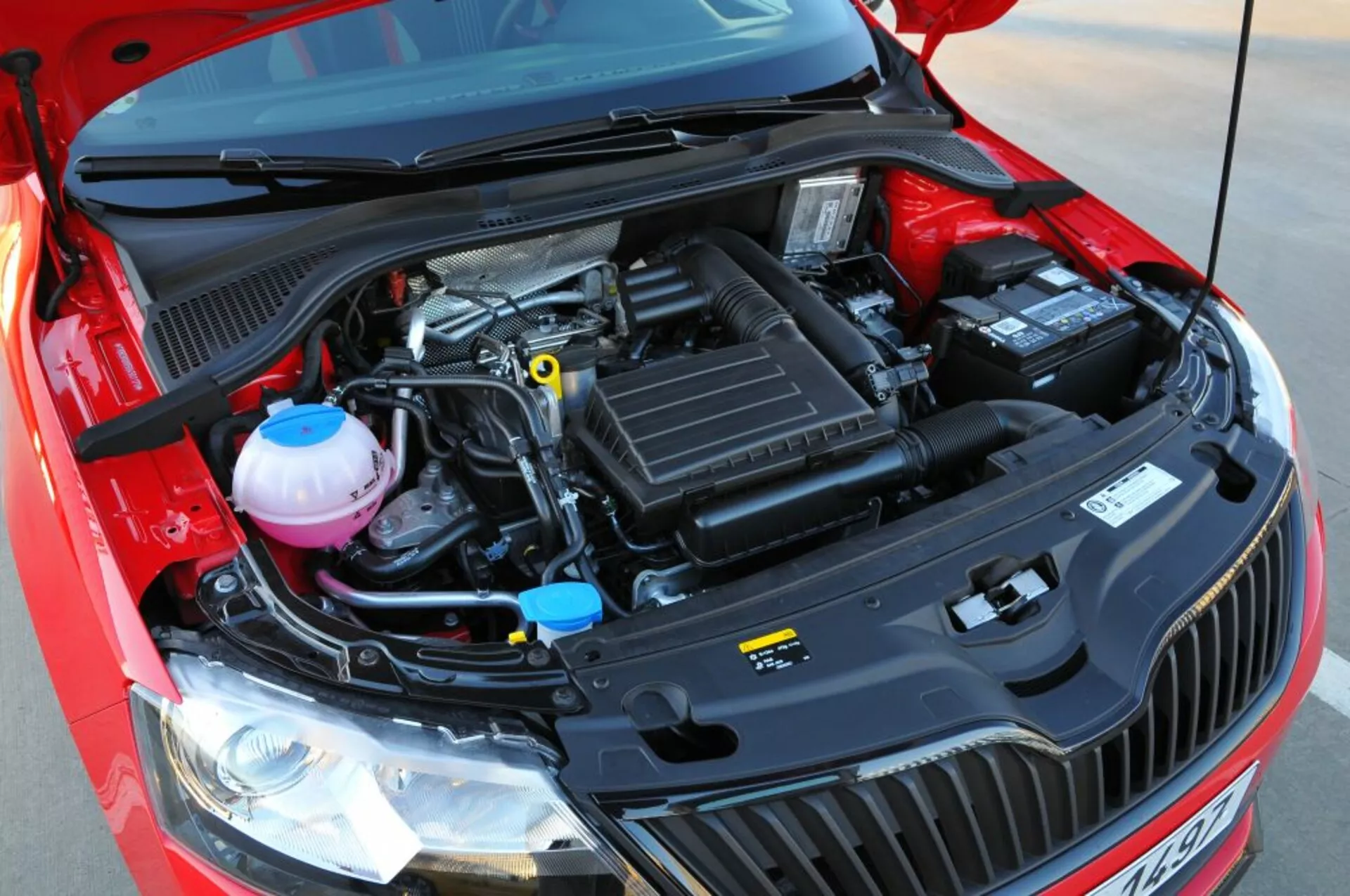 Podroben pogled na odprti motor Opel Astre 2005 (Astra TwinTop), ki poudarja mehanske komponente kot so zračni filter, pokrov motorja, rezervoarji za hladilno in zavorno tekočino ter baterijo iz rahlo dvignjene frontalne perspektive