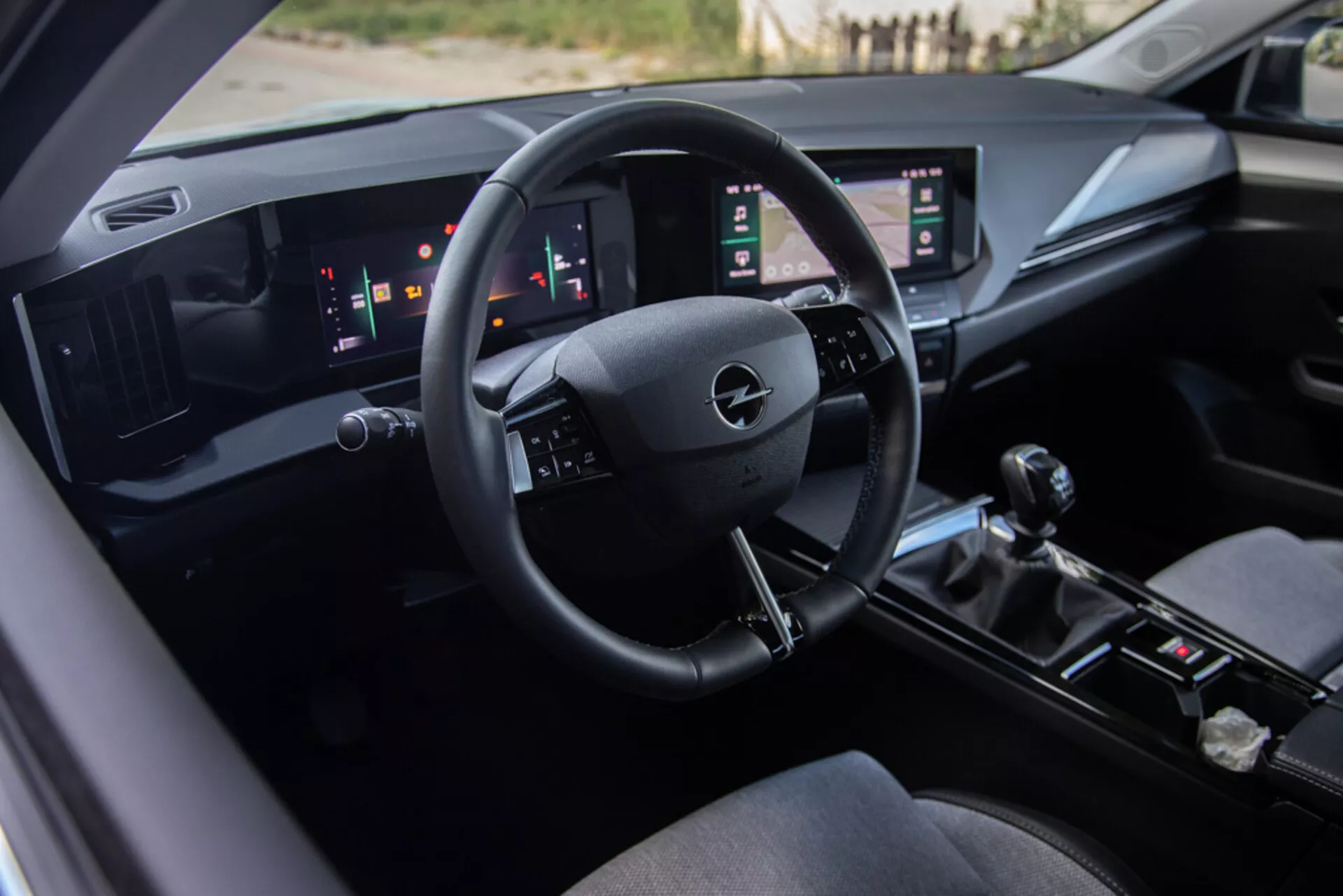Notranjost Opel Astre 2022 s sedežem voznika, tehnološko napredno armaturno ploščo z logotipom Opel na volanu, digitalnimi merilniki in dvojnimi navpičnimi zasloni na dotik