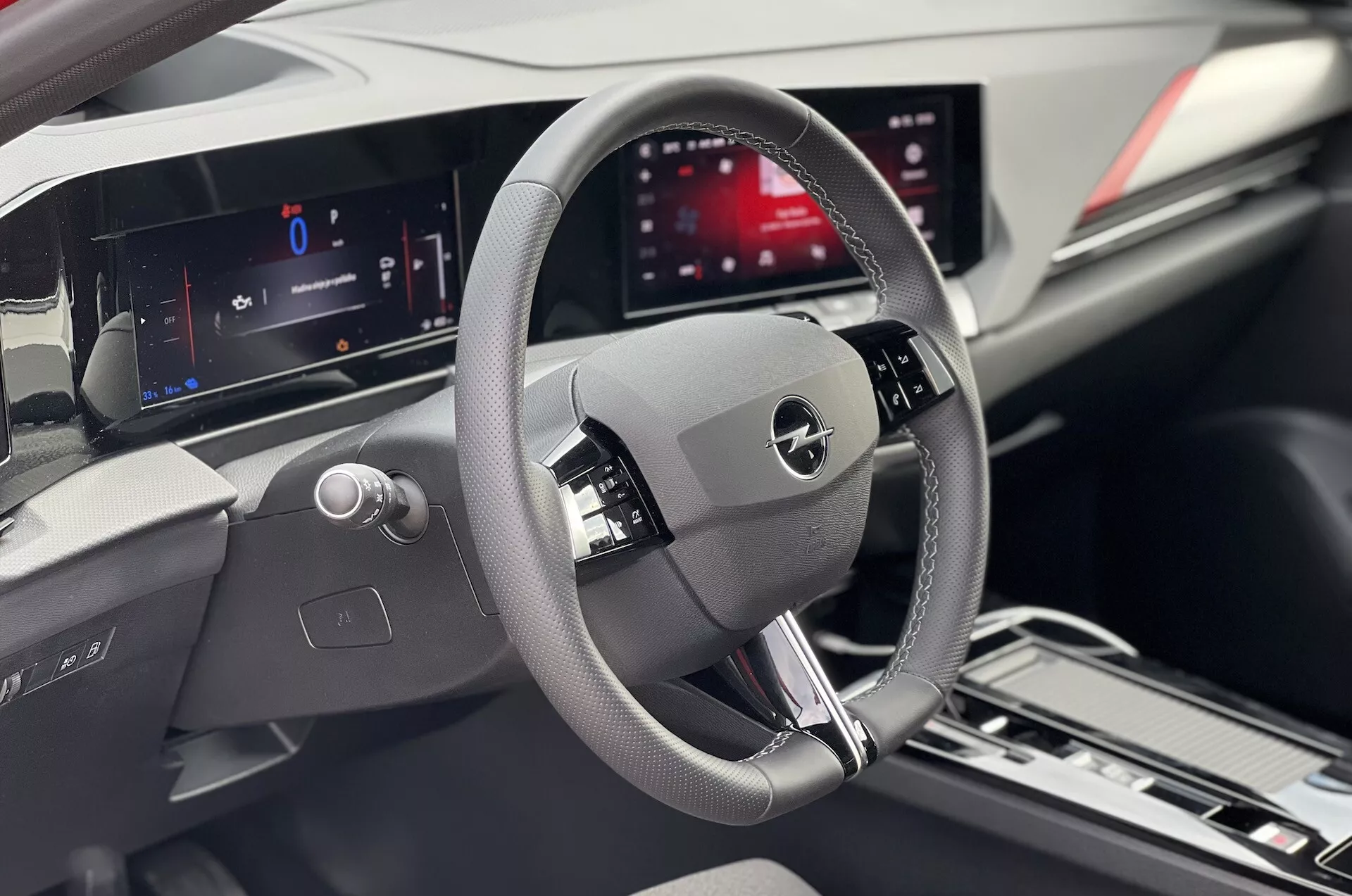 Pogled na notranjost Opel Astre 2022, osredotočen na voznikov prostor z detajlnim volanom, digitalno instrumentno ploščo in centralnim prikazovalnikom infotainmenta