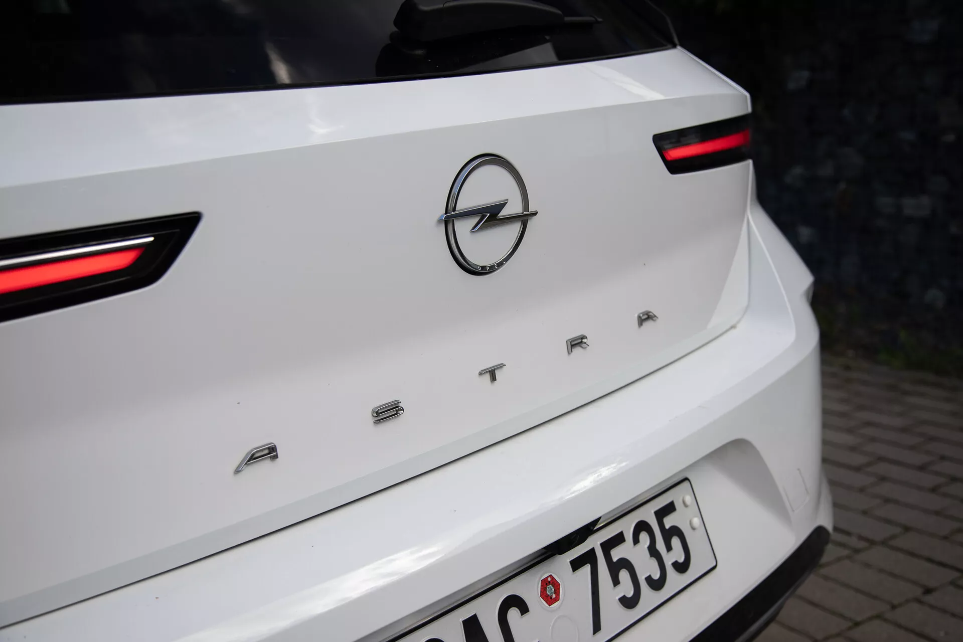 Podroben pogled na zadnji del belega Opel Astra letnik 2022, poudarjajoč LED zadnje luči, logotip Opel in ime modela 'ASTRA' na pokrovu prtljažnika
