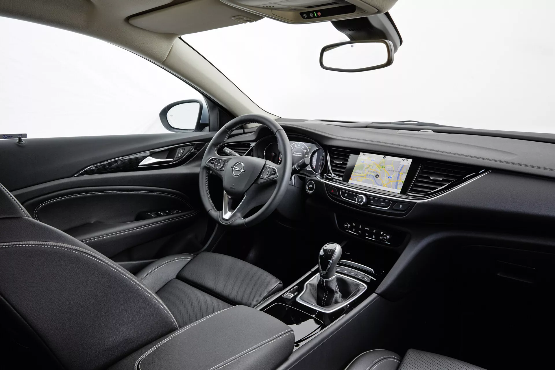 Notranjost Opel Insignia 2013 s multifunkcijskim volanom, digitalnim armaturnim ščitom, zaslonom na dotik z navigacijskim sistemom, avtomatskim menjalnikom z izbirnikom voznega načina, klimatsko napravo in usnjenimi sedeži z detajlnimi šivi, vse pod profesionalno studijsko razsvetljavo.