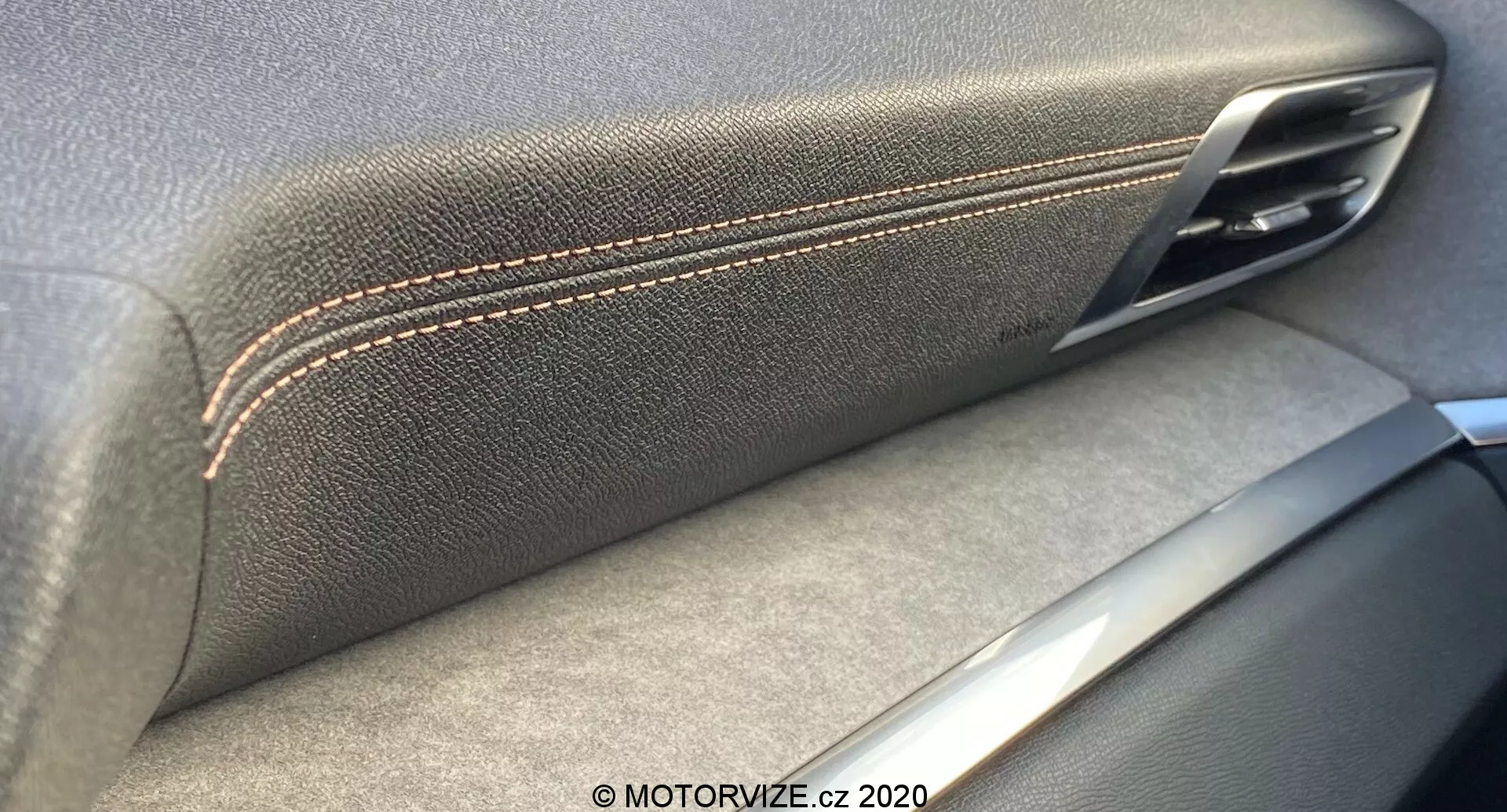 Zbližan posnetek notranjosti Peugeot 3008 2021 vrata, ki poudarja zlitje usnjenega naslonjala za roko s kontrastnimi šivi in kovinskim ročajem vrat. Srebrni poudarki nakazujejo na osredotočenost na izdelavo in kakovost materiala, s sencami, ki nakazujejo notranji vir svetlobe.