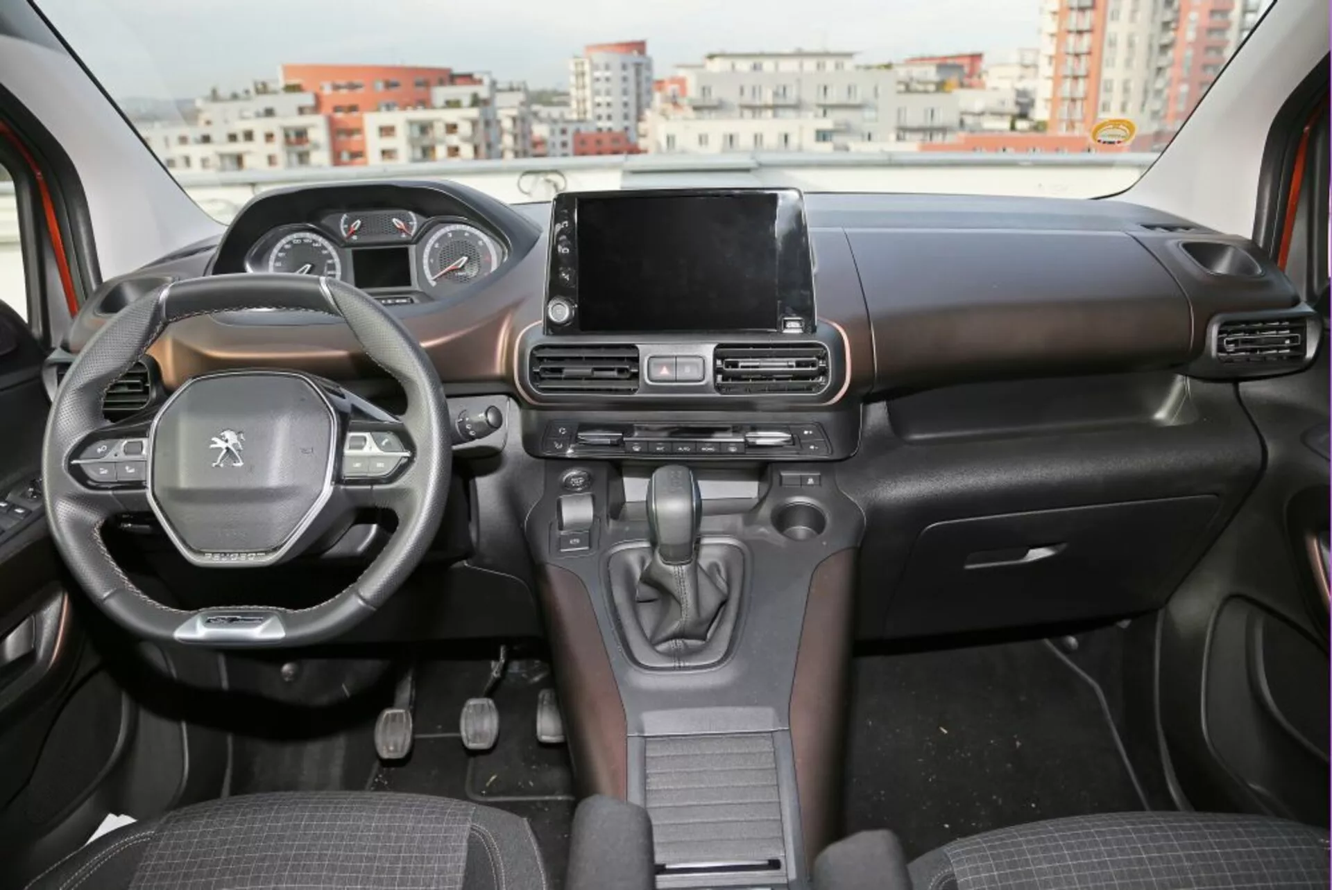 Notranji pogled na Peugeot 3008 iz leta 2016, ki prikazuje armaturno ploščo, volan z nameščenimi kontrolami in centralni zaslon na dotik infotainment sistema iz perspektive zadnjega sedeža