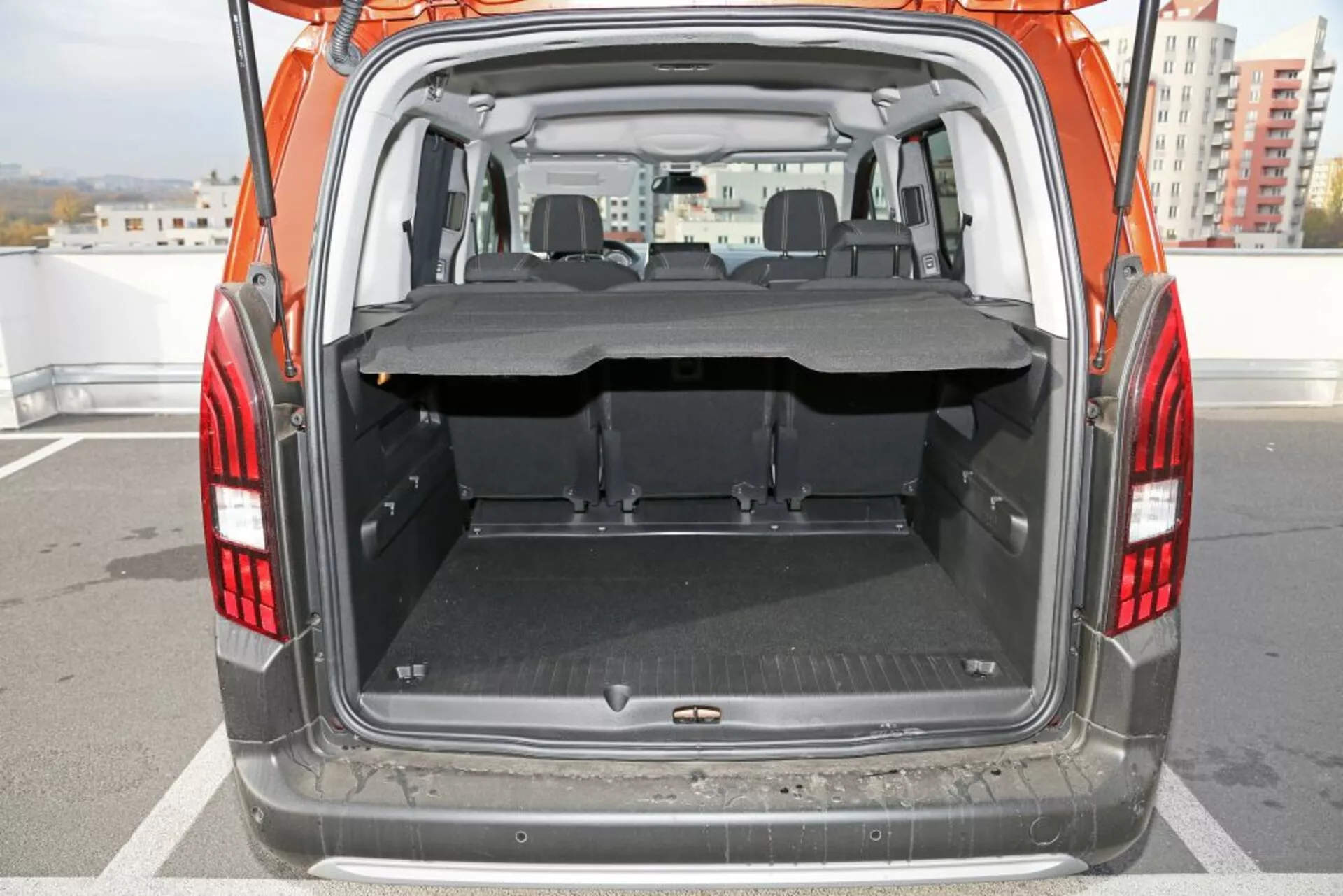 Zadnji pogled na SUV Peugeot 3008 iz leta 2016, osredotočen na odprt prtljažnik in tovorni prostor, prikazuje čisto ravno tla s zaščitno preprogo, delno izvlečeno prekrivalo za tovor, zložljive zadnje sedeže in jasen pogled na predel s sprednjimi sedeži skozi zadnji del.