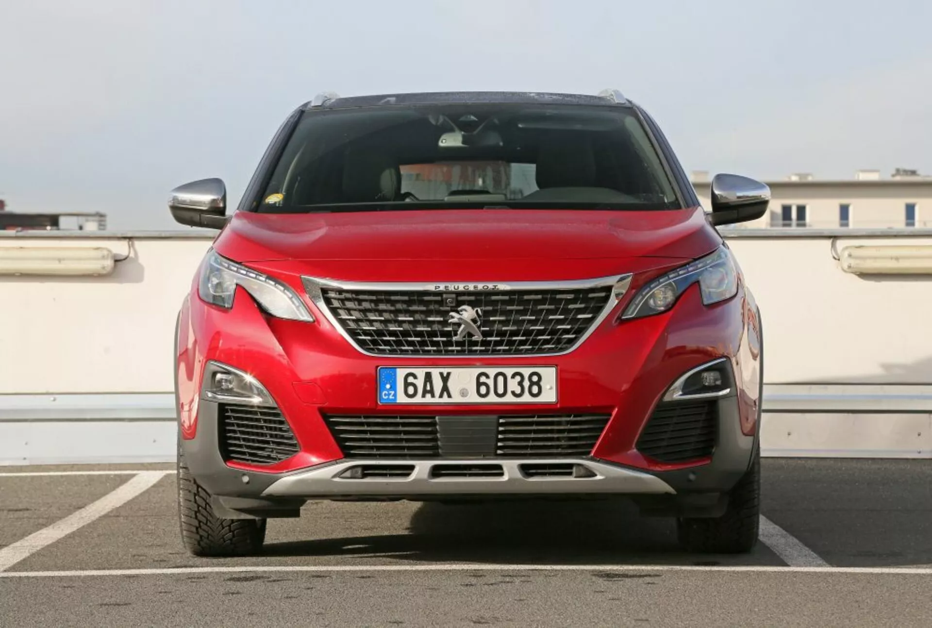 Sprednji pogled na rdeči Peugeot 3008 letnik 2016 s kromirano masko in emblemo, sodobnimi LED žarometi in elementi aerodinamične zasnove, fotografirano na prostem