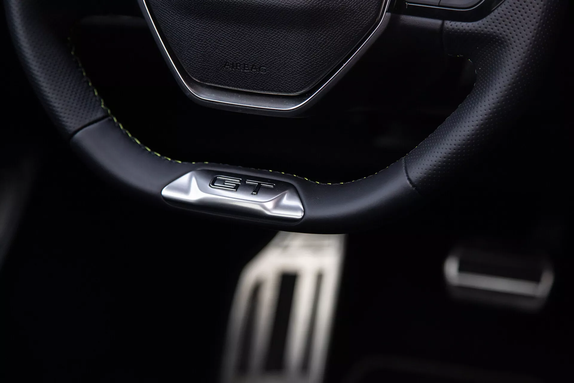 Notranjost Peugeota 408 leta 2023 osredotoča na športni volan z usnjenimi šivi in emblemo GT, kovinske pedale za zmogljivost in premium temne lastnosti kokpita